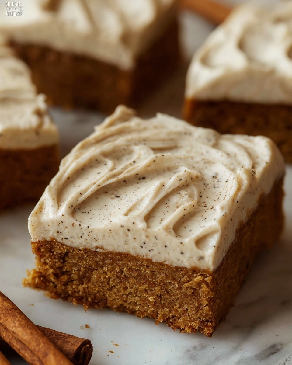 This image shows a close-up of a square piece of cake with two layers: the bottom layer is a moist, brown cake, and the top layer is a thick, creamy frosting with visible specks of spice spread smoothly with soft swirls. The cake is on a surface with white marbled texture, and there are cinnamon sticks near the bottom of the frame. Other similar cake pieces are blurred in the background, highlighting the front piece. photo taken with an iphone --ar 4:5 --v 7