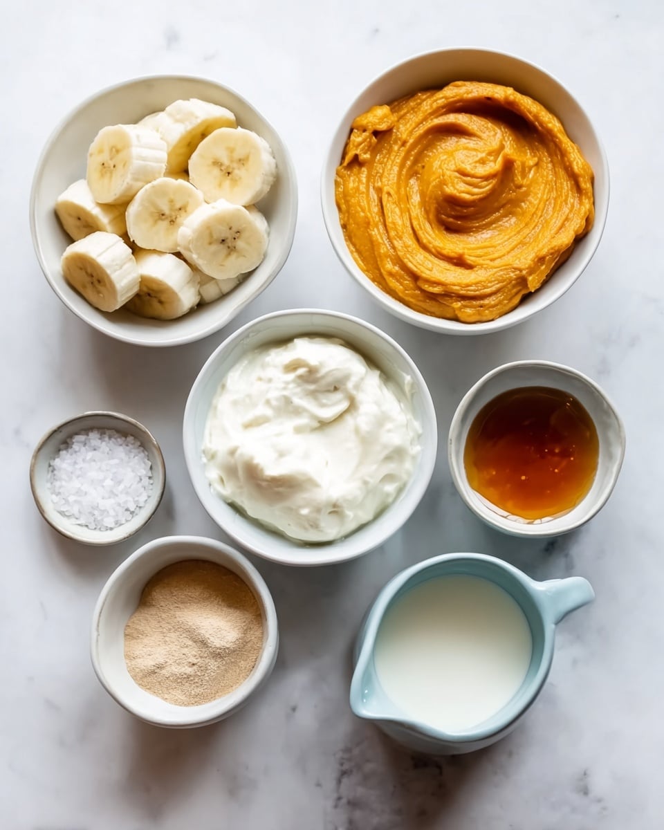 Seven white bowls and a small jug are placed on a white marbled surface. The top left bowl holds thick slices of banana, pale yellow with a soft texture. To its right is a larger bowl filled with bright orange, smooth pumpkin puree, swirled gently. Below the banana, a bowl contains creamy white yogurt with soft peaks. Next to it, a light blue jug holds a creamy white liquid, likely milk. Below the yogurt, a small bowl contains light brown powder, appearing dry and fine. To the right of it is a tiny bowl with amber-colored liquid, shiny and smooth. Further right is a medium bowl with darker amber liquid. At the bottom left, a small bowl with coarse white salt granules completes the layout. The image has a clean, soft light and is well arranged. photo taken with an iphone --ar 4:5 --v 7