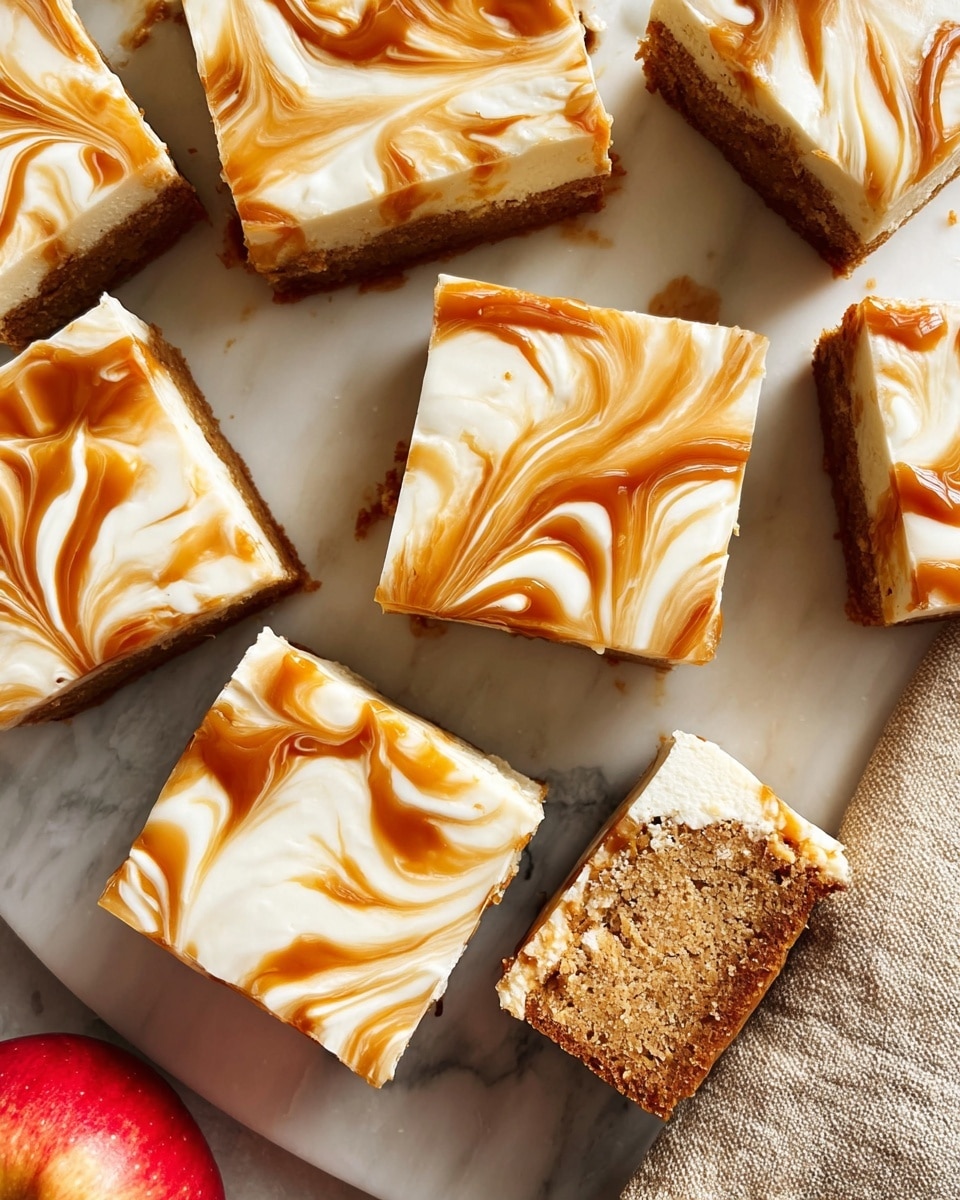The image shows several square pieces of a dessert on a white marbled surface. Each piece has two layers: a bottom light brown cake layer with a soft and crumbly texture, and a thick top layer of smooth white frosting with swirls of glossy caramel in shades of amber and light brown. The caramel swirls create a marbled pattern on the creamy frosting. Some pieces are closely packed while two pieces are slightly apart, showing the cake texture underneath. In the corner, part of a red apple is visible on a beige cloth. The scene is bright and clear, giving a fresh and inviting look to the dessert photo taken with an iphone --ar 4:5 --v 7