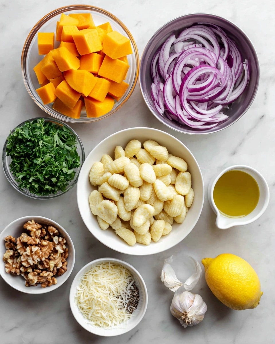 The image shows several bowls and a lemon arranged on a white marbled surface. At the center, there is a white bowl full of small gnocchi pieces, pale yellow in color with slight ridges. Above it to the left, a glass bowl holds bright orange cubes of butternut squash. To the top right, there is a metal bowl filled with thinly sliced red onions, displaying purple and white colors. Below the squash, a metal bowl contains fresh green parsley leaves. Below the gnocchi, there are three small white bowls: one with chopped walnuts showing brown textures, another with white shredded cheese, and one with white salt and black pepper mixed. To the right, two garlic cloves and a whole bright yellow lemon lie near a white cup filled with golden olive oil. Everything is neatly arranged with clear colors and textures. Photo taken with an iphone --ar 4:5 --v 7
