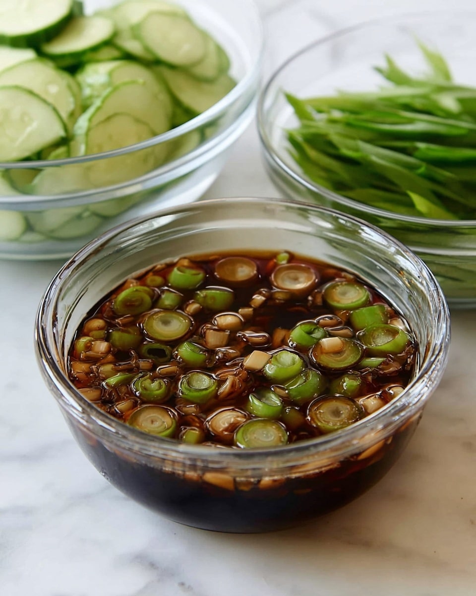 The image shows a clear glass bowl filled with a dark brown sauce that has many small round green and light tan slices of spring onions floating in it. Behind this bowl, there are two other clear glass bowls, one contains light green cucumber slices stacked loosely, and the other holds bright green piled sliced scallions. All the bowls sit on a white marbled surface, creating a clean and fresh look. photo taken with an iphone --ar 4:5 --v 7
