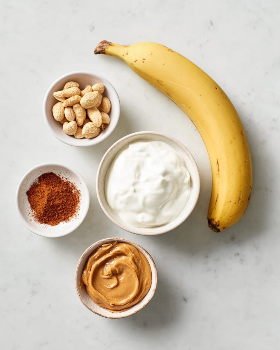 A white marbled surface holds five items arranged in a circle: a whole yellow banana on the right, a small white bowl with smooth light brown peanut butter at the bottom right, a small white bowl with reddish-brown cinnamon powder at the bottom left, a small white bowl with roasted peanuts at the top left, and a medium-sized white bowl filled with thick white yogurt in the center. The bowls show different textures, with the yogurt smooth and creamy, the peanut butter glossy and dense, the peanuts dry and rough, and the cinnamon powder fine and powdery. photo taken with an iphone --ar 4:5 --v 7