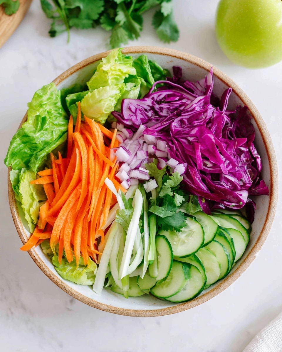 A white bowl with a rough tan edge holds a colorful salad arranged in neat sections: bright green lettuce leaves form the base, topped with thin orange carrot sticks on the left, finely sliced white and light green scallions above them, vibrant purple shredded cabbage next to the scallions, and curved slices of light green cucumber on the right. The bowl sits on a white marbled surface with a green apple blurred in the top right corner and some cilantro leaves in the bottom left. photo taken with an iphone --ar 4:5 --v 7