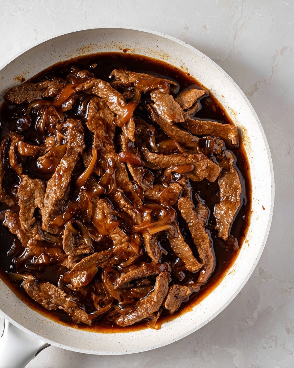 A white cast iron pan filled with strips of browned meat covered in a shiny, dark brown sauce, showing rich textures with some pieces slightly curled and others flat, creating a mix of smooth and rough surfaces; the dark sauce pools around the meat, giving a glossy look, all placed on a white marbled surface photo taken with an iphone --ar 4:5 --v 7