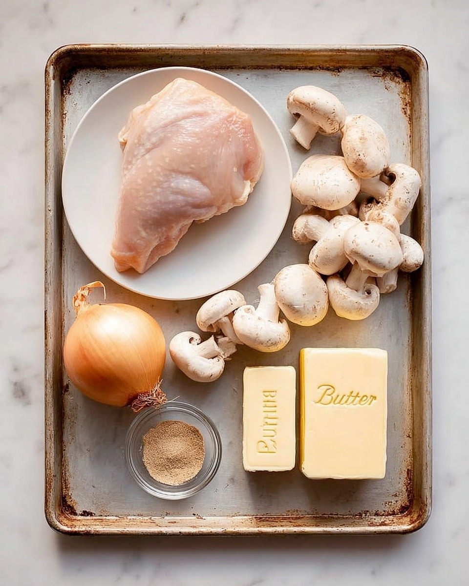 A white plate holds a raw light pink chicken piece positioned on the left side of a large, worn metal tray with a light grey surface. On the right side of the tray, there is a pile of white and light brown mushrooms stacked in a loose group. Below the mushrooms, a whole onion with light golden brown skin is placed. Near the bottom left of the tray, there is a small glass bowl containing a fine brown powder. Next to it, two pieces of pale yellow unsalted butter, one in a rectangular block with a wrapper labeled