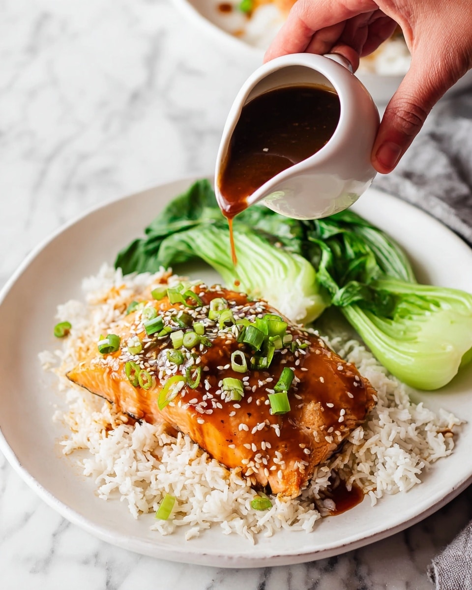 A white plate holds a bed of fluffy white rice as the base layer. On top, there is a piece of cooked salmon with a shiny orange glaze, sprinkled with white sesame seeds and green chopped scallions. To the right of the salmon and rice, there are fresh green leafy bok choy leaves. A woman's hand is shown pouring a dark brown sauce from a small white pitcher over the salmon, with the sauce flowing smoothly and adding a glossy texture to the fish. The whole scene is set against a white marbled surface. photo taken with an iphone --ar 4:5 --v 7