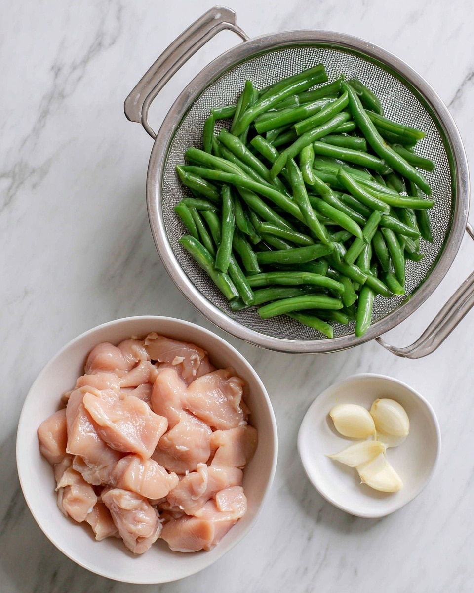 There is a metal colander filled with fresh, bright green cut green beans on top right, showing their smooth texture and vibrant color. Below it, on the bottom left, is a white bowl with raw, light pink chicken pieces coated in a shiny marinade, the pieces smooth and irregular in shape. Next to the bowl on the right, there is a small white bowl holding three peeled garlic cloves, which are creamy white and smooth. All items are placed on a white marbled surface. Photo taken with an iphone --ar 4:5 --v 7