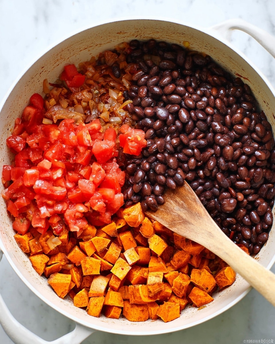 In a white cooking pot on a white marbled surface, there are three main layers of ingredients side by side. On the left, bright red diced tomatoes mixed with small brown bits of cooked onions form a chunky and slightly moist layer. On the right, a pile of shiny dark brown beans sits, covering part of the diced sweet potatoes which make up the bottom layer, showing their orange color and soft texture with some cooked onions mixed in. A wooden spoon rests inside the pot, touching the ingredients. Photo taken with an iphone --ar 4:5 --v 7