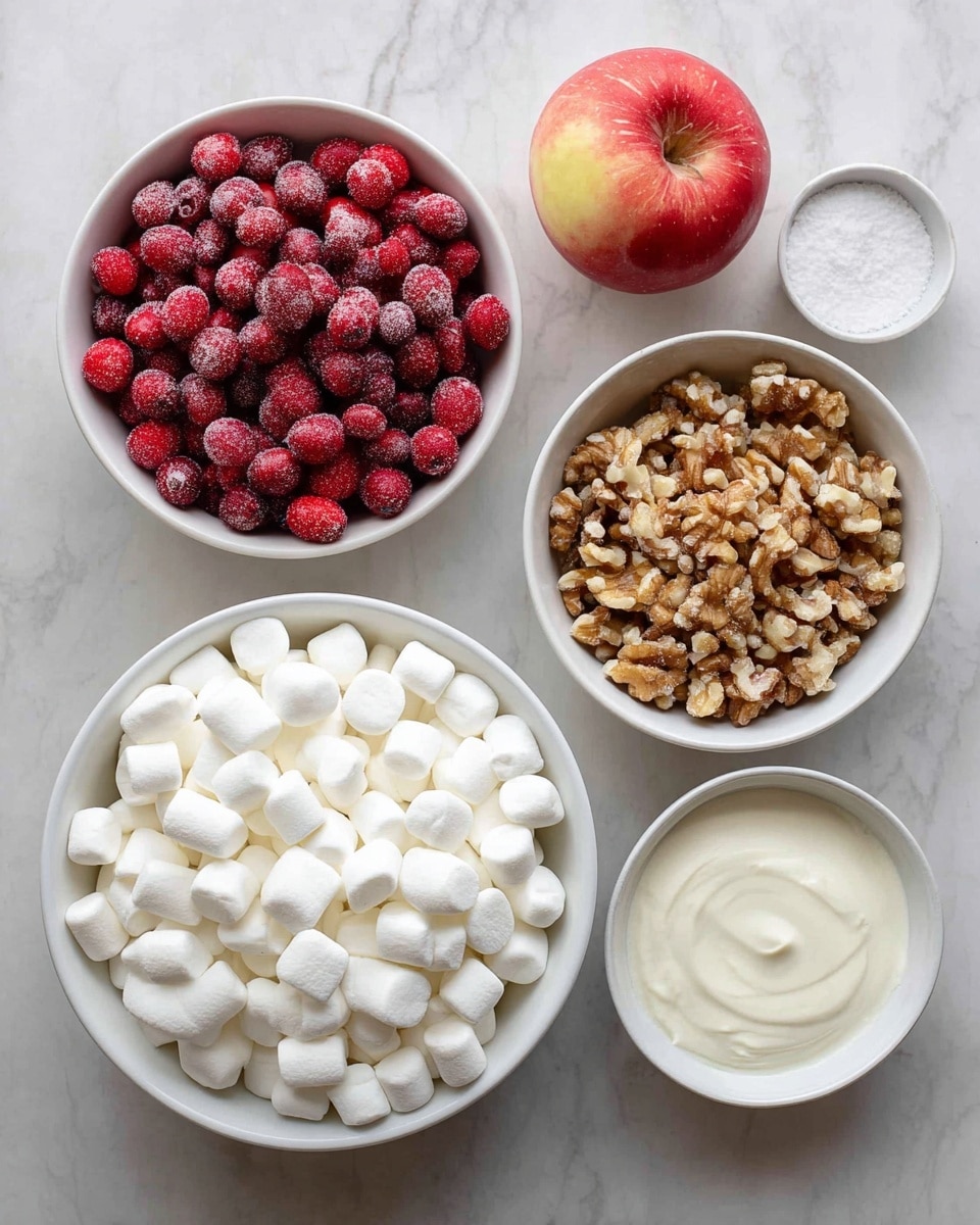 The image shows six ingredients neatly arranged on a white marbled surface. At the bottom center is a large white bowl filled with small, soft white marshmallows. Above it, on the left, is a white bowl filled with bright red frozen cranberries that have a frosty texture. On the right side next to the cranberries is a bowl with chopped walnuts, light brown in color, and beside it is a whole red apple with a slightly yellow tint near the top center. Below the walnuts are two small white bowls: one filled with white sugar and the other with a thick cream that is also white. The layout is clean and well-organized, showing the ingredients clearly. photo taken with an iphone --ar 4:5 --v 7