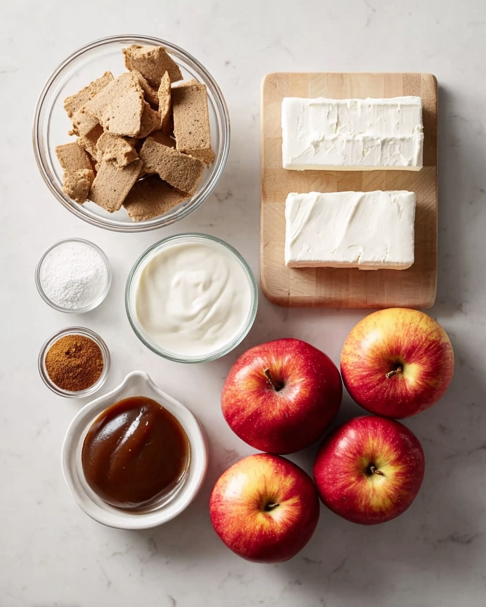 The image shows ingredients for a dessert arranged neatly on a white marbled surface. On the right, two rectangles of white cream cheese sit on a small light wooden board. Next to them are four bright red apples with yellow around the stem, rounded and shiny. Below the apples is a small white bowl filled with white powdered sugar, fluffy and fine in texture. To the left, a clear glass bowl contains broken pieces of light brown graham crackers with rough edges. Above it is a clear measuring cup filled with white cream. Next to the cream is a small white bowl with smooth caramel sauce in a rich brown color. In the bottom left corner, a bottle cap holds a small amount of dark vanilla extract, and beside it is a tiny clear bowl with ground cinnamon, dark golden brown in color. Everything is clean and organized with bright natural lighting, photo taken with an iphone --ar 4:5 --v 7