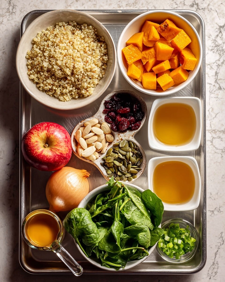 The image shows a metal tray holding several white bowls and small containers filled with ingredients arranged neatly. In the top left, there is a large white bowl full of light beige quinoa grains with a fluffy texture. To the right of it, a medium white bowl contains small, bright orange cubes of roasted butternut squash. Below, a white square bowl has three sections filled with tan slivered almonds, dark red dried cranberries, and green pumpkin seeds. A smaller white bowl to the right holds finely chopped green spring onions. Another large white bowl is filled with fresh, green spinach leaves with a slightly shiny texture. Toward the bottom left of the tray, a bright red and yellow apple sits next to a peeled shallot and a small metal cup filled with mustard. Finally, a clear measuring cup holds an orange-colored liquid, while two white ramekins hold smaller amounts of golden-yellow liquids. The tray is placed on a background with a white marbled texture photo taken with an iphone --ar 4:5 --v 7