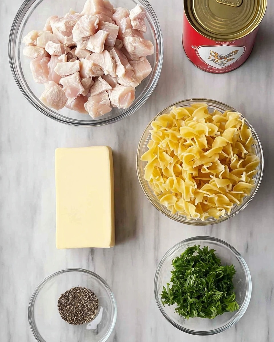 There are six items arranged on a white marbled surface. In the top left, there is a clear glass bowl filled with cubed cooked chicken, pale pink and white in color. To its right, another clear glass bowl holds uncooked yellow egg noodles with a twisted shape. Below the chicken, a solid light yellow stick of butter rests directly on the surface. To the right of the butter, there is a red and white can with a gold emblem, standing upright. Below the butter and slightly left, a small clear bowl contains fresh green parsley leaves. In the bottom left corner, a small clear bowl holds black pepper. photo taken with an iphone --ar 4:5 --v 7