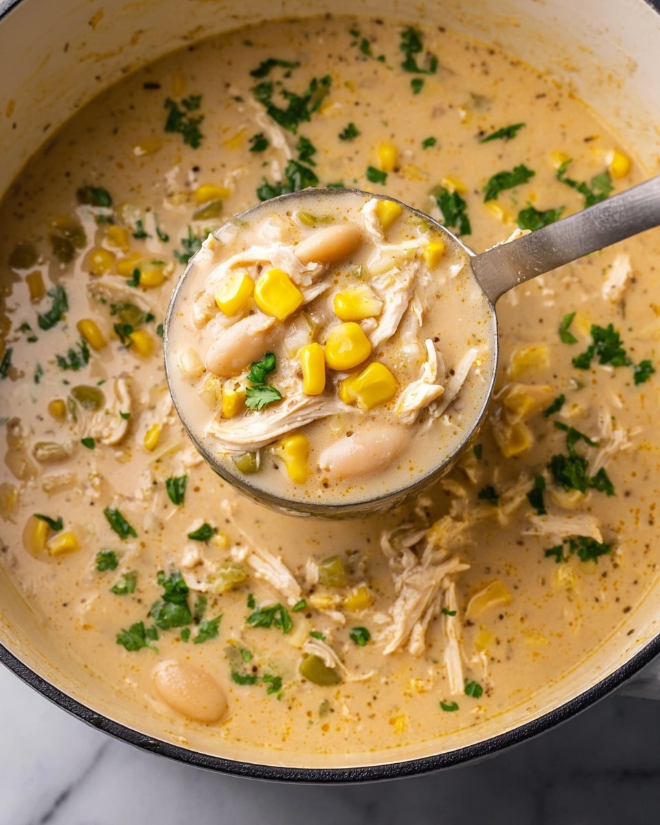 This image shows a close-up of a creamy soup in a large white pot with one layer of thick, light beige broth mixed with shredded white meat, yellow corn kernels, white beans, small green pieces, and bits of fresh green herbs sprinkled on top. A metal ladle, filled with the same soup showing all the ingredients in clear detail, is being held above the pot as if scooping the soup. The background is a white marbled surface. photo taken with an iphone --ar 4:5 --v 7
