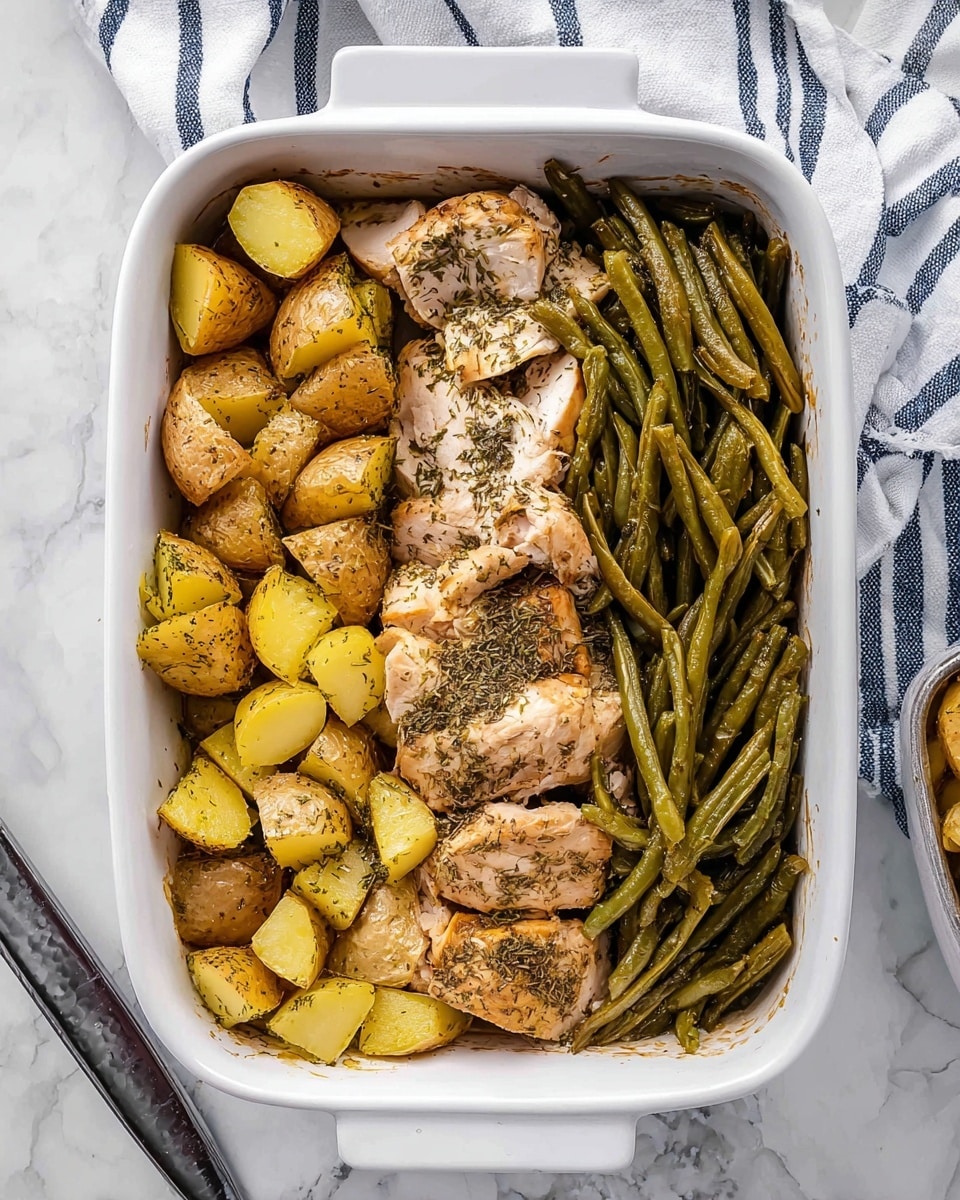 A white rectangular baking dish contains three main sections: on the left, there are golden-brown potato chunks seasoned with herbs, their texture slightly soft and rustic with some skin left on; in the middle, pieces of cooked chicken with a pale, tender inside and a light golden outside sprinkled evenly with dried herbs; on the right, a pile of green beans cooked to a darker green color, their texture slightly wrinkled from roasting. The dish is placed on a white marbled surface with a striped white and navy cloth napkin and a pan handle visible nearby. Photo taken with an iphone --ar 4:5 --v 7
