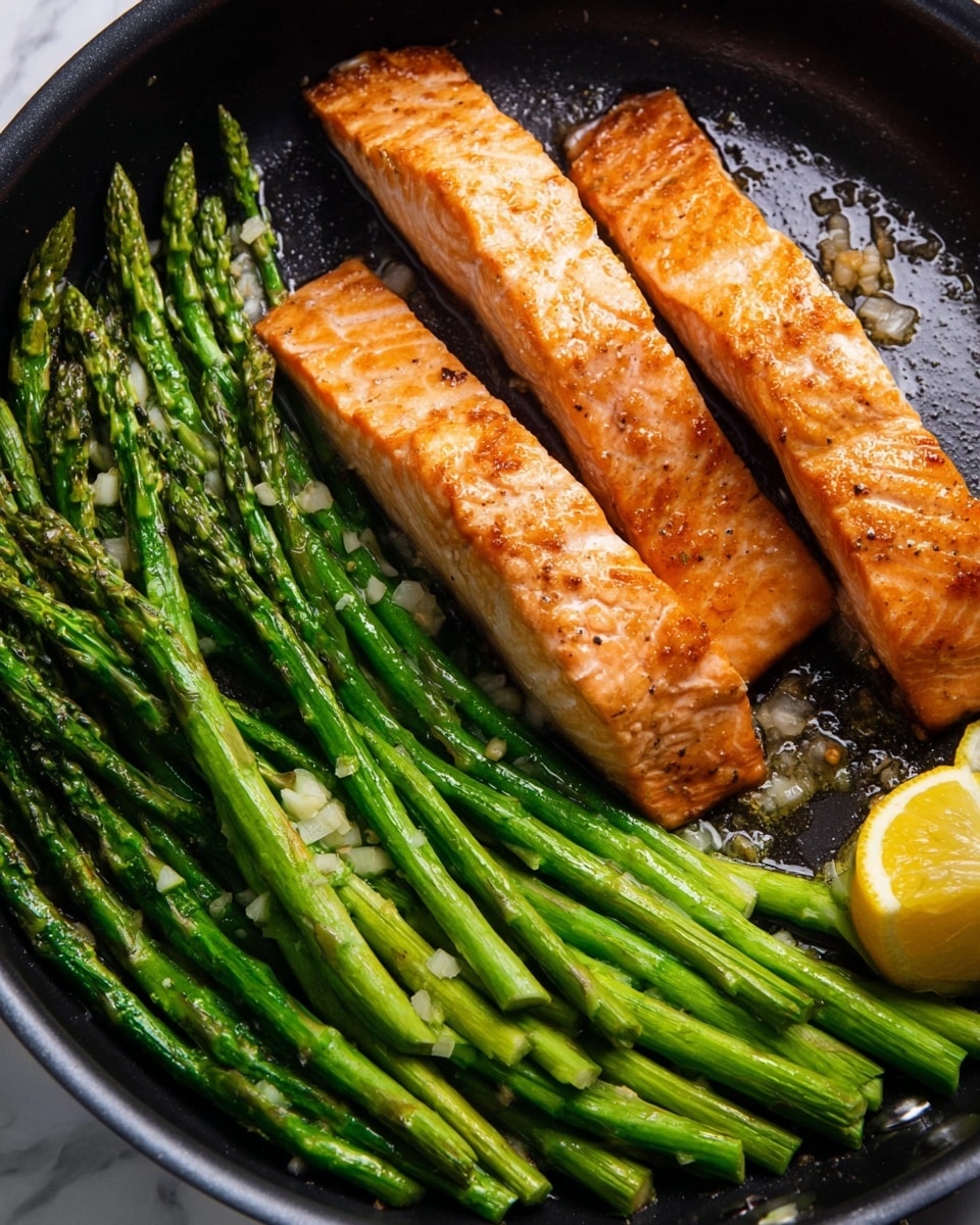 The image shows a black pan with three long, golden brown cooked salmon strips on the right side, each topped with small pieces of garlic. On the left side, there is a layer of bright green cooked asparagus spears, coated in oil with bits of garlic scattered on top. At the bottom right corner of the pan, there is a small slice of yellow lemon. The pan is placed on a white marbled surface. Photo taken with an iphone --ar 4:5 --v 7