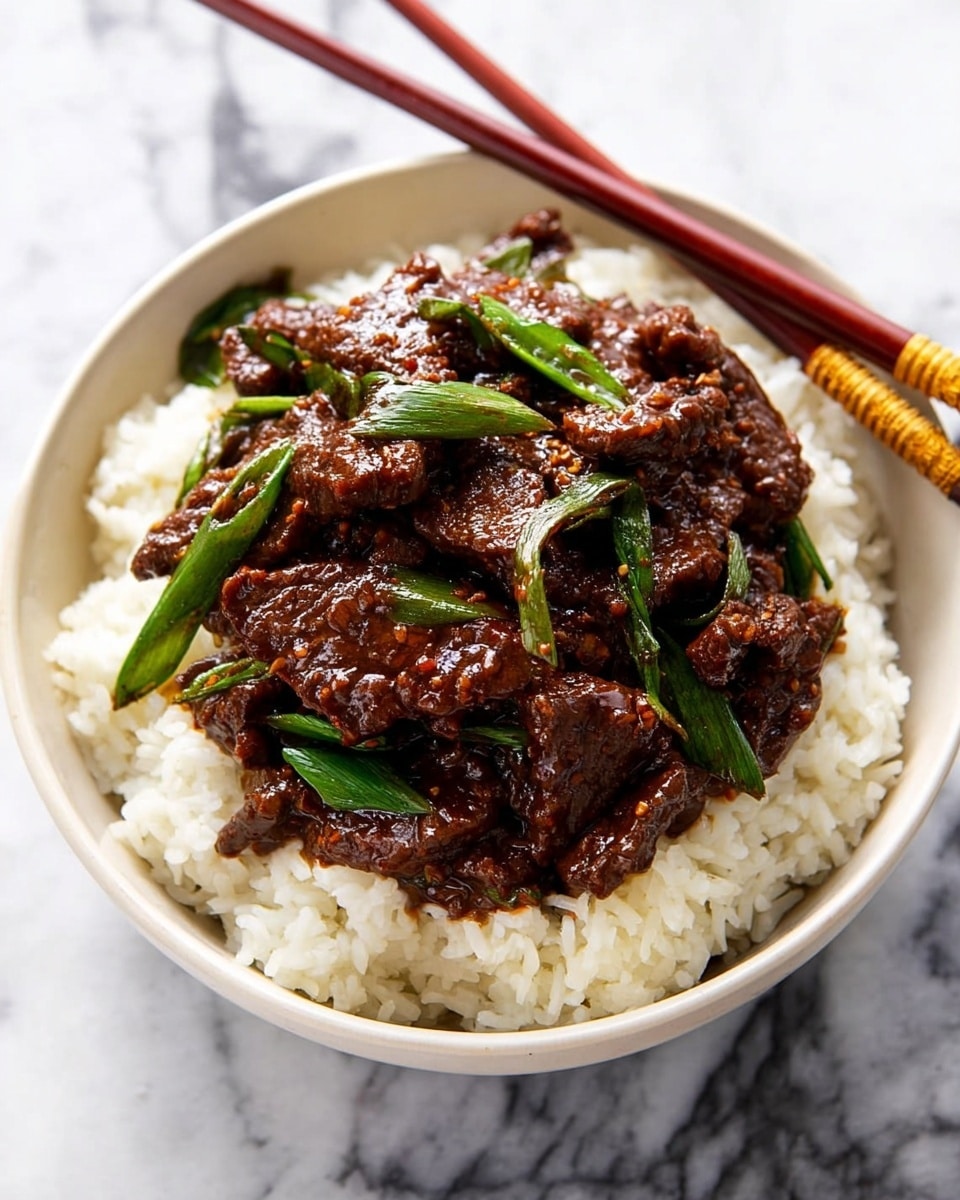 A white bowl filled with a base layer of fluffy white rice showing individual grains, topped with a thick layer of dark brown, glossy beef strips cooked in a rich sauce. Bright green pieces of scallion are scattered among the beef, adding contrast and freshness. The bowl is on a white marbled surface, and a pair of reddish-brown chopsticks with golden ends rest above the bowl. The photo taken with an iphone --ar 4:5 --v 7