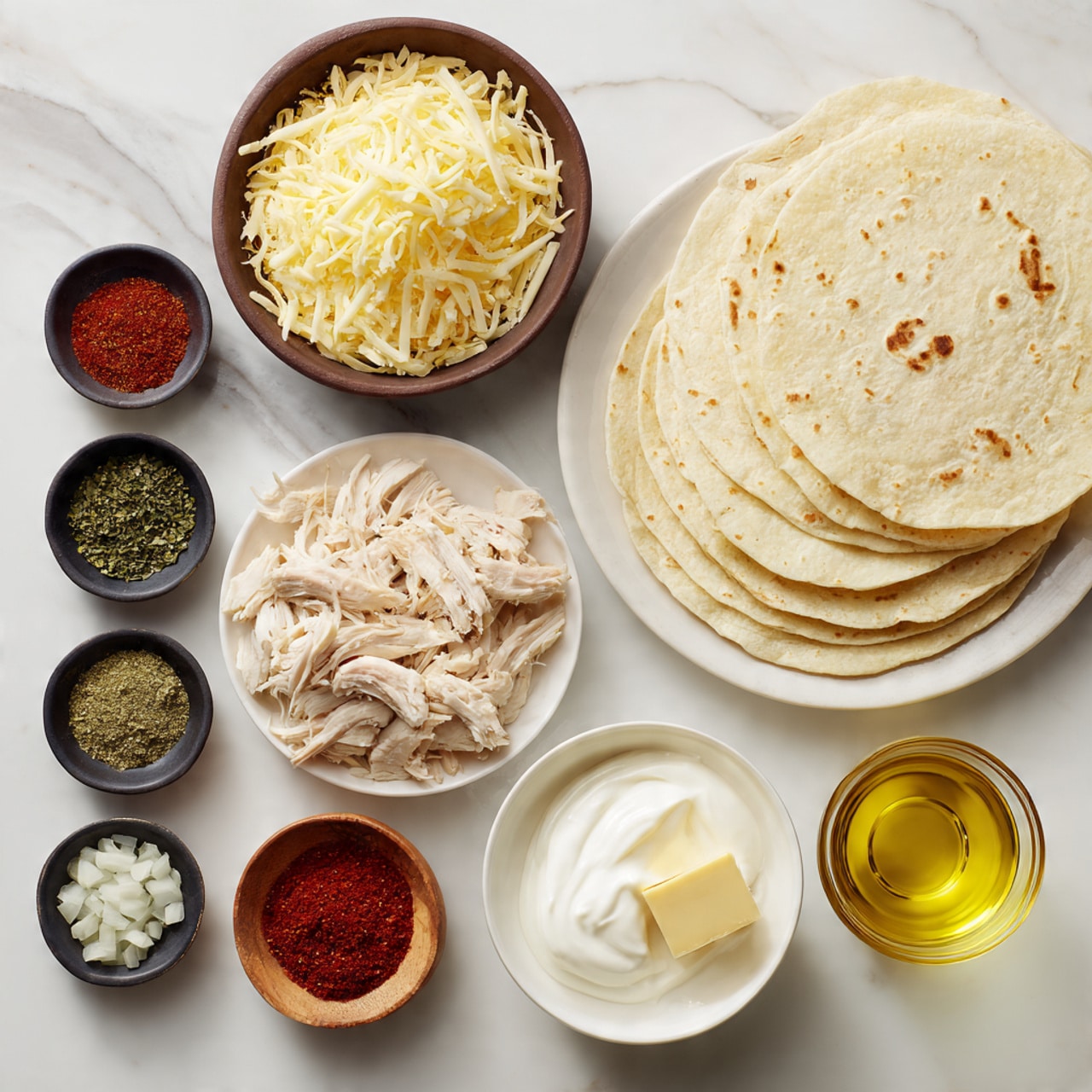 The image shows an arrangement of ingredients on a white marbled surface. There are three layers of light beige tortillas stacked on the top right. Below them is a white plate with shredded light brown cooked chicken. To the left, a dark brown bowl is filled with a heap of pale yellow shredded cheese. A small white bowl near the cheese holds a smooth dollop of white sour cream. Just below that is a small white bowl with a square piece of pale yellow butter. Near the top left are four small black bowls with different spices: green herb flakes, bright red chili powder, small white chopped onions, and a greenish ground spice in a small wooden bowl. A round clear glass bowl with a golden yellow liquid (oil) sits near these spices. The layers and colors create a balanced and neat display of ingredients for a dish photo taken with an iphone --ar 4:5 --v 7