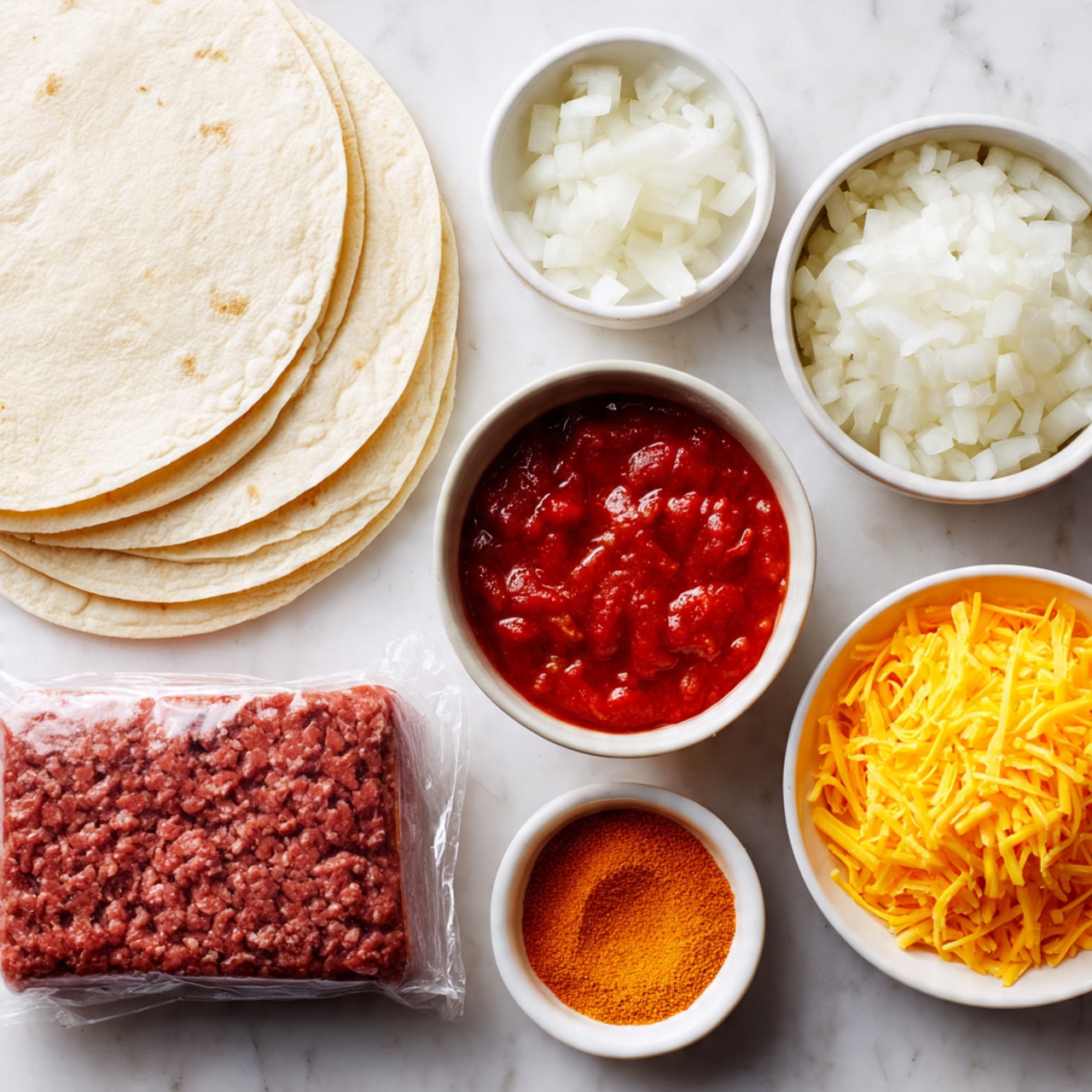 The image shows the ingredients for making tacos arranged neatly on a white marbled surface. There are four soft white tortillas stacked in the top left corner, next to a rectangular block of raw ground beef wrapped in clear plastic at the bottom left. On the right side, there are four small round white bowls: the top bowl holds chopped white onions with a clear texture, the middle right bowl contains a bright orange taco seasoning powder, below it is a bowl filled with chunky red salsa with visible tomato pieces, and the bottom bowl has a small mound of shredded yellow cheddar cheese. The photo taken with an iphone --ar 4:5 --v 7