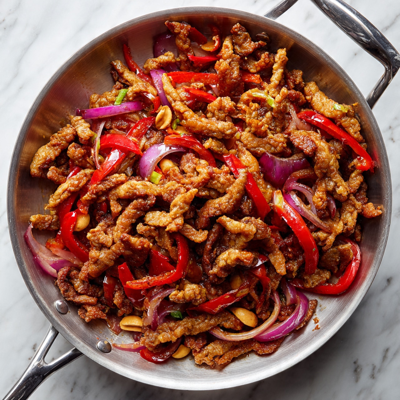A large silver pan filled with several pieces of crispy, golden-brown fried meat strips scattered around the pan. Mixed in are thin slices of red bell peppers and red onions, some lightly charred. In the center, a vibrant and glossy red sauce covers some of the meat, adding a shiny texture. Small light-colored nuts or seeds peek through the layers under the meat and vegetables. The pan is set on a white marbled surface showing a part of a stove. photo taken with an iphone --ar 4:5 --v 7