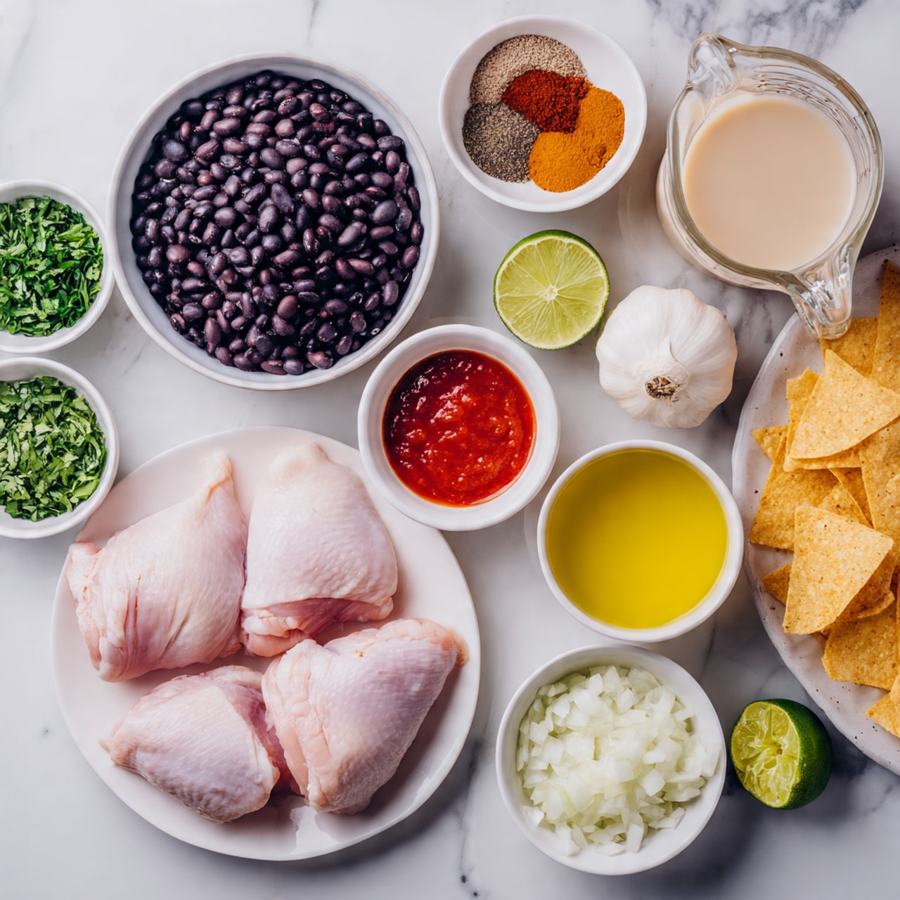 The image shows many small white bowls and dishes on a white marbled surface, each holding different ingredients. In the center right, there is a white plate with five raw pale pink chicken thighs. To its left, a white bowl is filled with shiny black beans. Above that are several small bowls with chopped green herbs, garlic, green chopped peppers, spices in light brown, reddish, and dark brown powders, and a bowl of red salsa sauce. On the far right, there is a white bowl with light yellow liquid and half a lime cut in half beside it. There is also a clear measuring cup with a white creamy sauce and a large glass jug with brown broth. Another white bowl holds chopped onions, and a bowl with small pieces of white tortilla chips is on the bottom right corner. Photo taken with an iphone --ar 4:5 --v 7