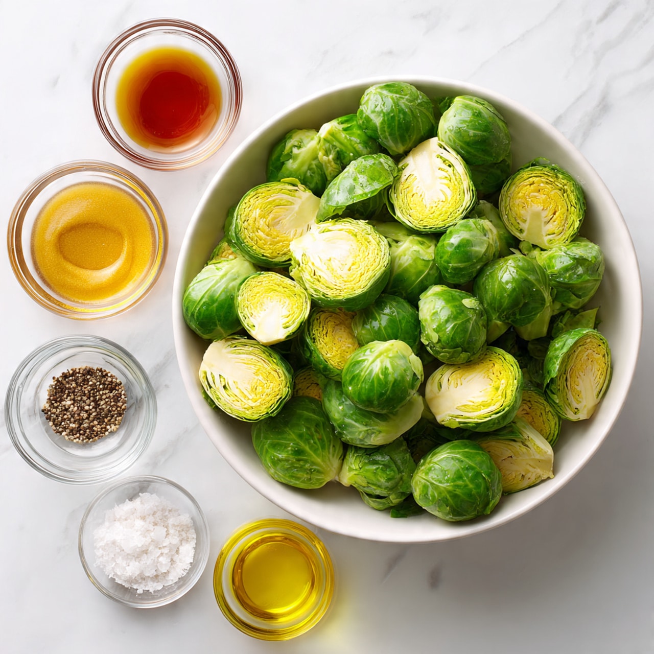 The image shows a white bowl full of green brussels sprouts halves placed on the right side of a white marbled surface. On the left side, there are five small clear glass bowls arranged in two rows: the top row has a bowl of amber maple syrup, a bowl of light brown apple cider vinegar, and a bowl of yellow Dijon mustard. The bottom row has a bowl with white salt and black pepper, and another bowl filled with golden olive oil. Each bowl is labeled with bold black text. The scene is bright and clear, with all ingredients neatly arranged. Photo taken with an iphone --ar 4:5 --v 7