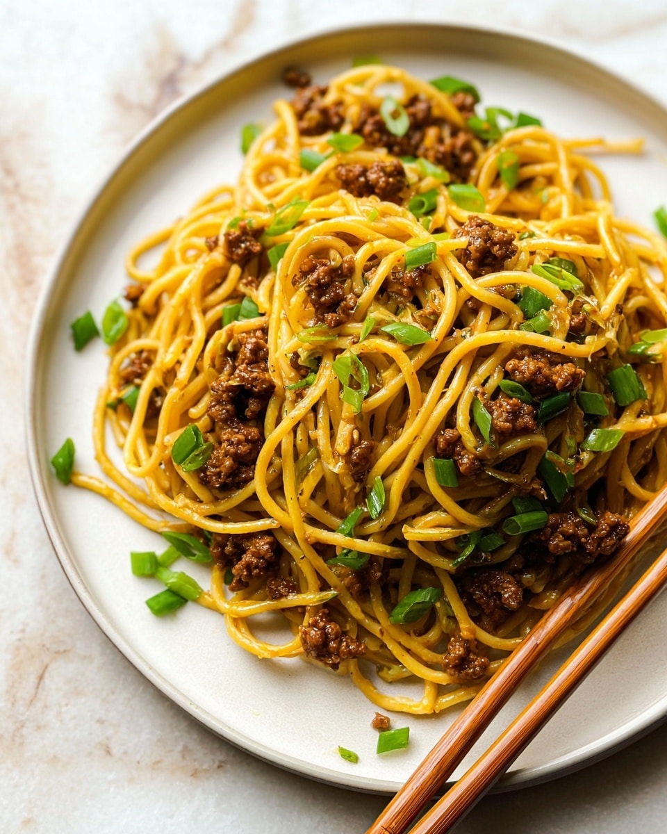 A mound of golden yellow spaghetti noodles sits on a white plate, entwined with small, dark brown crumbled meat pieces mixed throughout. Bright green chopped scallions are scattered on top and around the noodles, adding a fresh contrast. Two light brown wooden chopsticks rest on the edge of the plate, pointing diagonally into the food. The plate is placed on a white marbled textured surface that enhances the colors of the dish. photo taken with an iphone --ar 4:5 --v 7