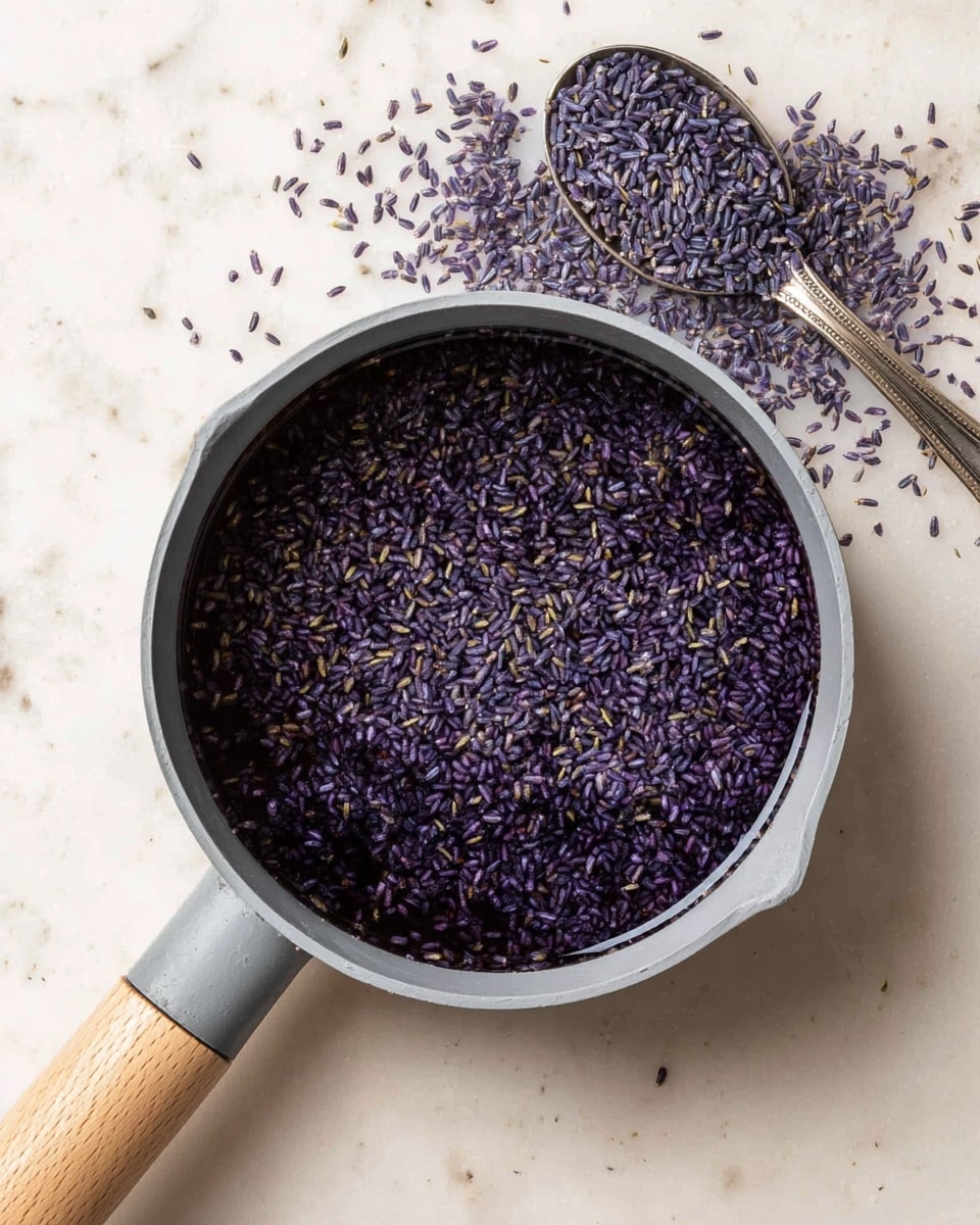 The image shows a light gray saucepan with a wooden handle filled with a dark liquid, covered with many small purple and green rice grains floating evenly on the surface. The saucepan is placed on a white marbled surface, and above it, there is a silver spoon with more purple grains spilled around it. The texture of the liquid looks smooth and reflective, contrasting with the matte finish of the rice grains. photo taken with an iphone --ar 4:5 --v 7