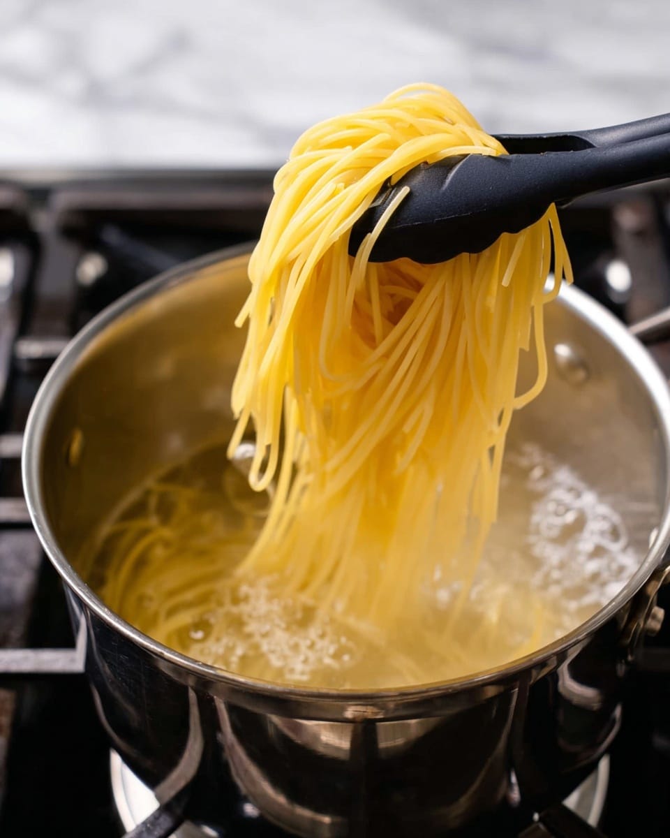 The image shows yellow cooked spaghetti being lifted out of a silver pot of boiling water with a black pasta server. The noodles are long, smooth, and slightly shiny, hanging in loose strands over the server's prongs. The pot has water bubbling around the edges, and the stove beneath the pot is visible with a dark burner. The setting has a white marbled surface in the background, adding a clean look to the scene. photo taken with an iphone --ar 4:5 --v 7