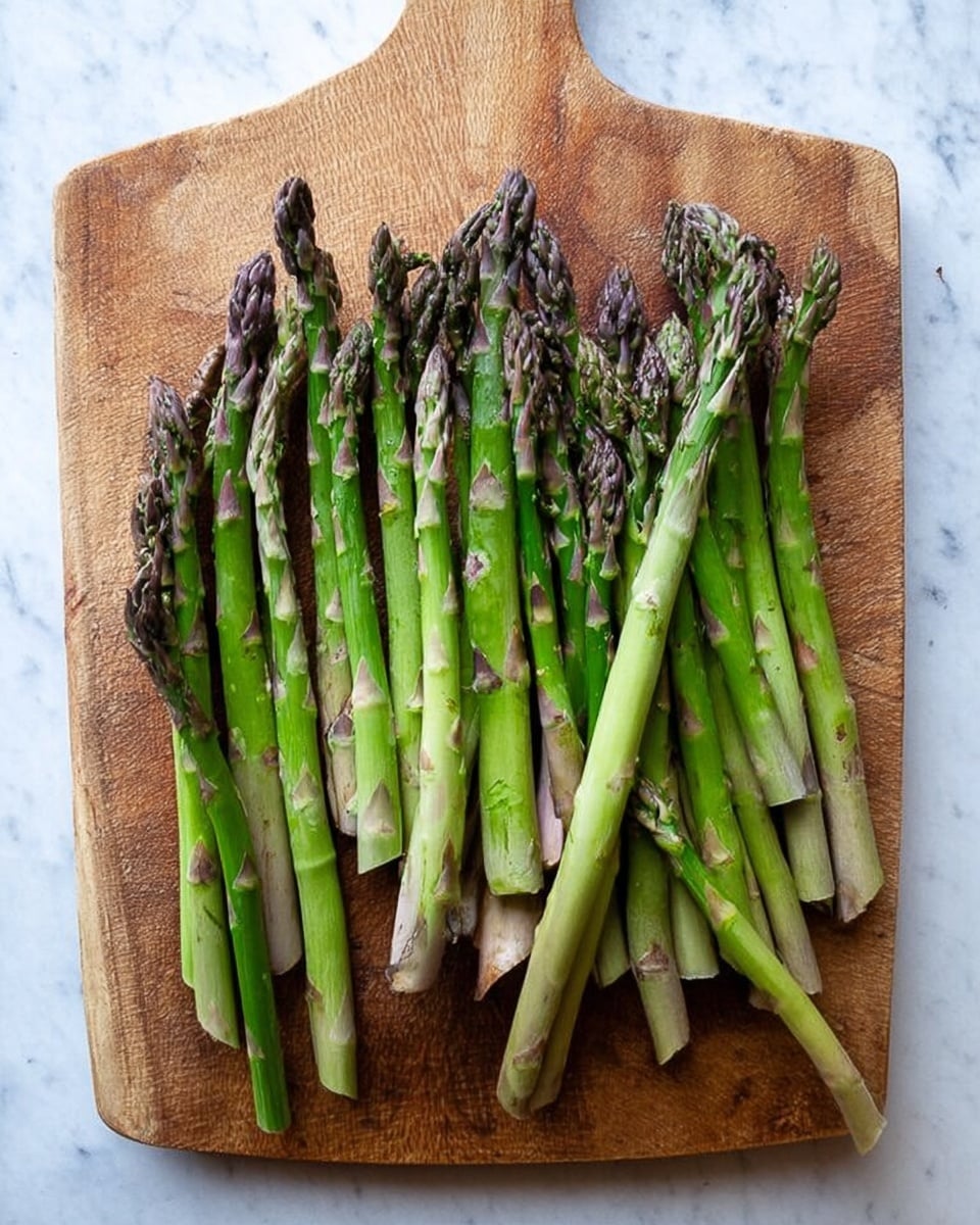 A wooden cutting board with a rustic look is placed on a white marbled surface. On the board, there are many fresh green asparagus stalks lined up close to each other. The asparagus varies in size, some thick and some thin. The tips are dark green with a slightly purple shade and have a soft texture, while the lower parts are lighter green with small brown marks. The overall look is neat and natural, showing fresh vegetables ready to be cooked photo taken with an iphone --ar 4:5 --v 7