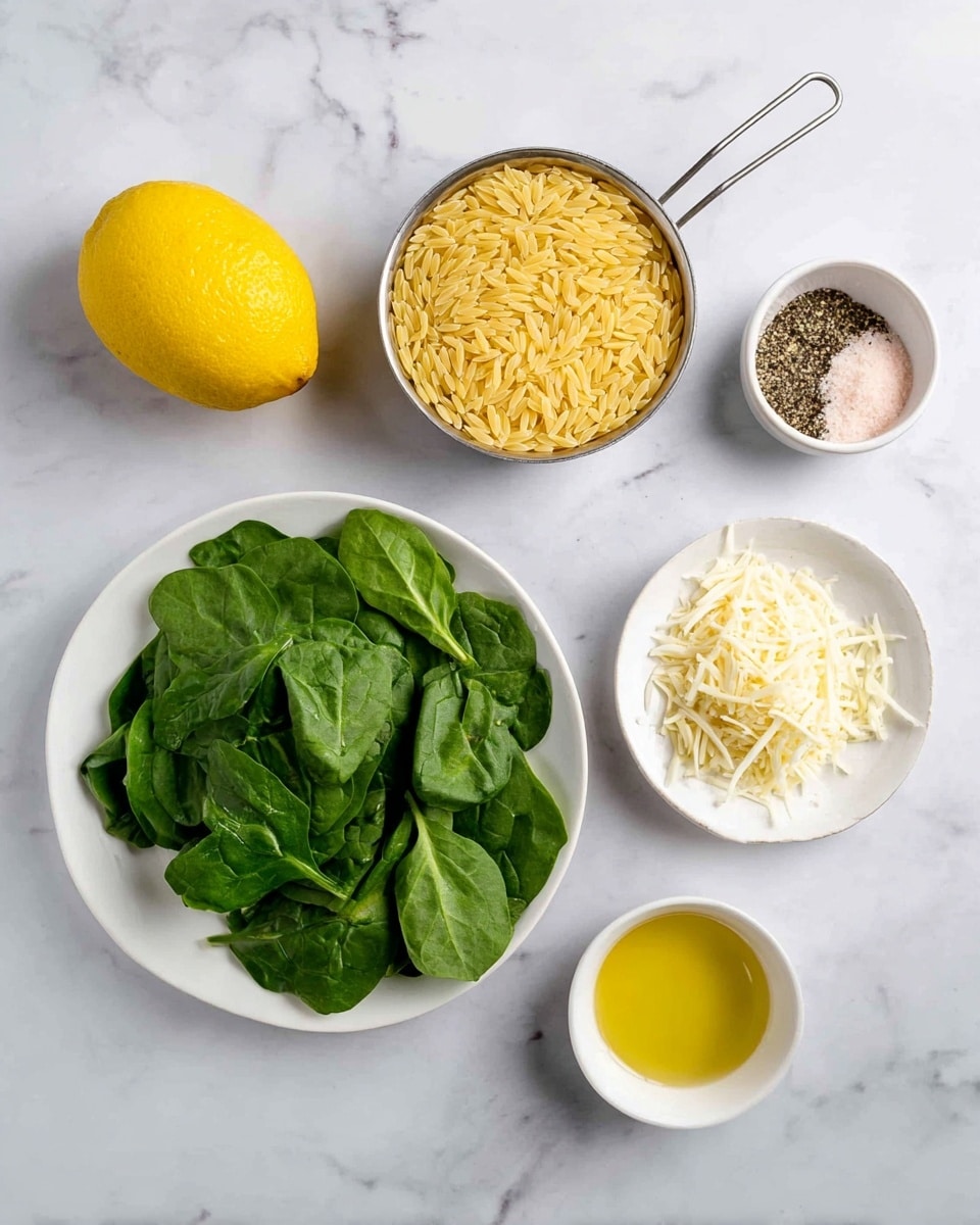 A top-down view of six ingredients arranged on a white marbled surface: a whole yellow lemon on the top left, a metal measuring cup filled with uncooked yellow orzo pasta on the top right, a small white bowl with a mix of black pepper and pink salt on the middle right, a medium white plate filled with fresh green spinach leaves in the center, a small white bowl with shredded pale yellow cheese on the bottom left, and a small white bowl containing yellow olive oil on the bottom right photo taken with an iphone --ar 4:5 --v 7