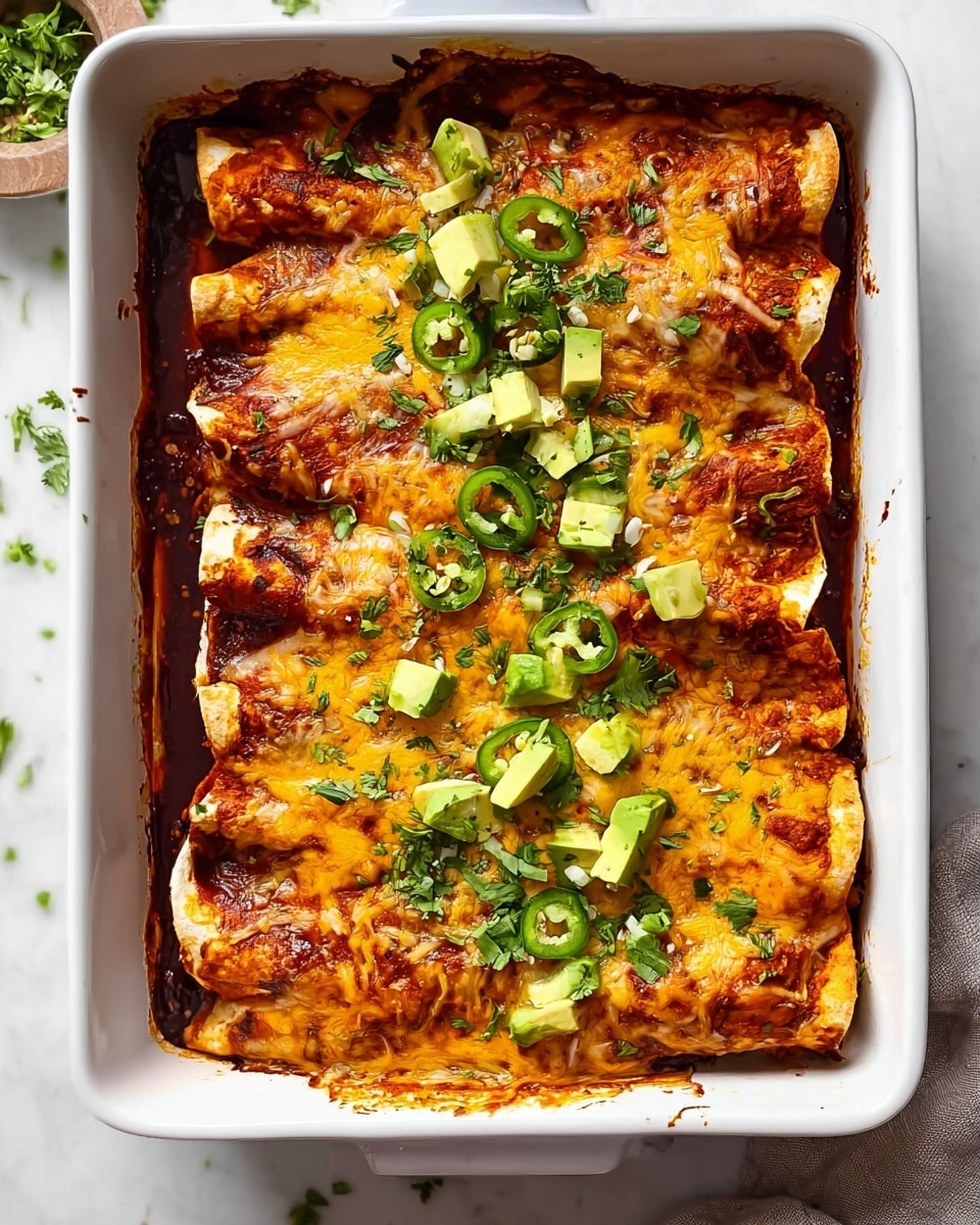 This image shows a white rectangular baking dish with four enchiladas placed side by side. Each enchilada has a layer of soft golden-brown tortillas filled with a reddish sauce and melted yellow cheese on top with slightly crispy browned edges. On top of each enchilada are scattered pieces of green sliced jalapeños, small chunks of light green avocado, and finely chopped fresh cilantro sprinkled evenly over the dish. The enchiladas are slightly bubbling with sauce overflowing and sticking to the sides of the white baking dish. The dish is set on a white marbled textured surface with some green herbs visible around the edges. Photo taken with an iphone --ar 4:5 --v 7