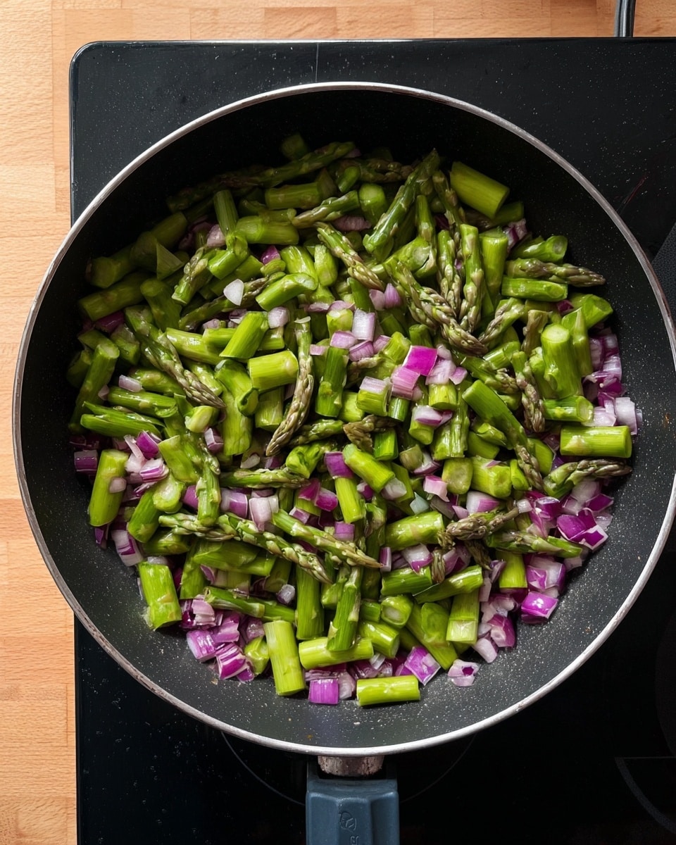 A black pan filled with a mix of chopped green asparagus pieces layered on top of finely diced purple-red shallots. The asparagus pieces are thick and cut evenly, showing their fresh green color and textured tips. The shallots form a bright purple-red base beneath the asparagus, adding contrast. The pan is placed on a black induction stove, and the background is a wooden surface. photo taken with an iphone --ar 4:5 --v 7