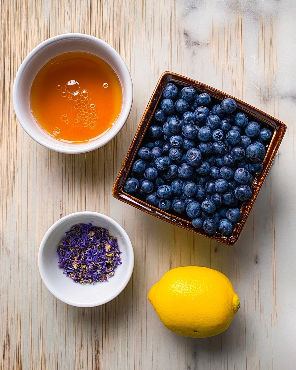 The image shows four items arranged on a white marbled surface. At the top center, there is a square basket filled with many small, round blueberries that are a deep blue color. To the left, there is a white bowl with an orange-colored liquid that has some small bubbles inside. Below the basket, slightly to the left, there is another white bowl containing small purple flower petals. On the far right side, there is a bright yellow lemon sitting directly on the surface. Photo taken with an iphone --ar 4:5 --v 7