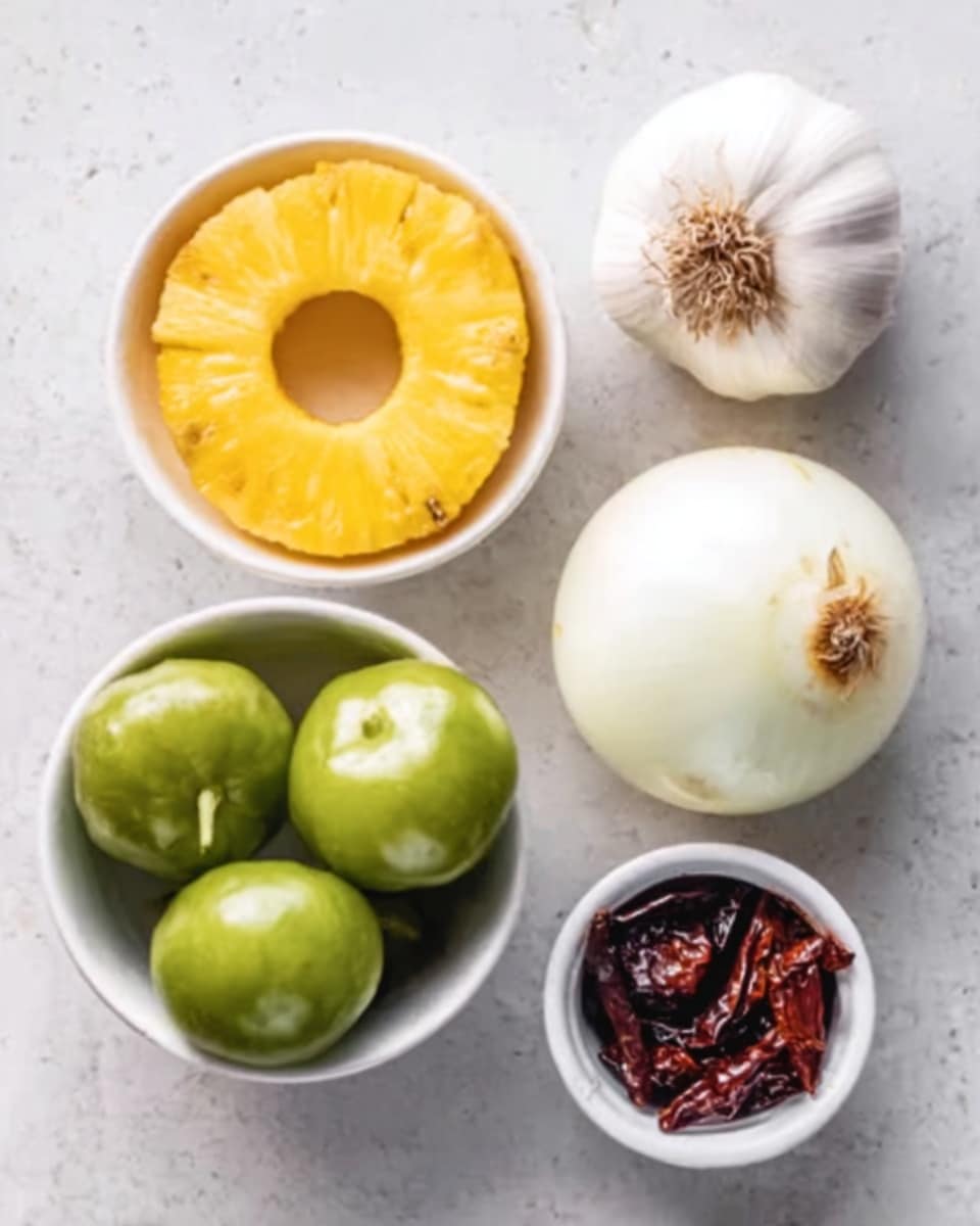 The image shows five different food items placed on a white marbled surface. On the top left, there is a white bowl filled with a bright yellow pineapple ring. To the right of it, a whole white onion rests with a bit of root showing. Below the onion, there is a garlic bulb with its papery skin intact. On the bottom left, a white bowl contains five small, shiny green tomatillos, each round and smooth. Finally, on the bottom right, there is a small white cup holding some dark red dried chiles. The items are arranged neatly and spaced apart. photo taken with an iphone --ar 4:5 --v 7