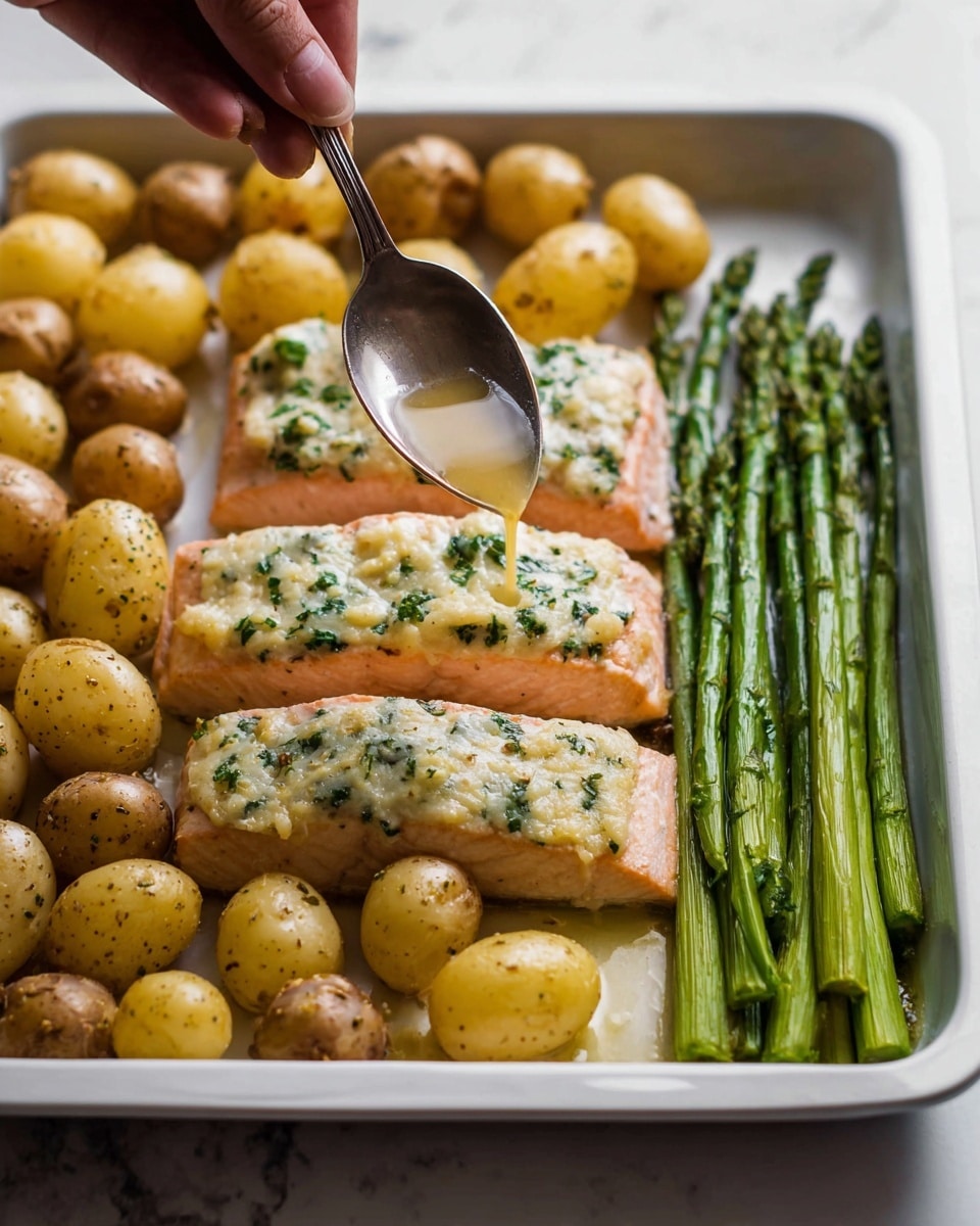 A white baking tray is filled with three main layers: small golden brown baby potatoes covering the left side, two light pink salmon fillets in the center topped with a speckled layer of melted herbs and cheese, and a row of bright green asparagus spears arranged neatly on the right side. A woman's hand is holding a silver spoon above the middle salmon fillet, pouring a clear liquid sauce that glistens as it falls, highlighting the moist texture of the fish. The scene is set on a white marbled surface. photo taken with an iphone --ar 4:5 --v 7