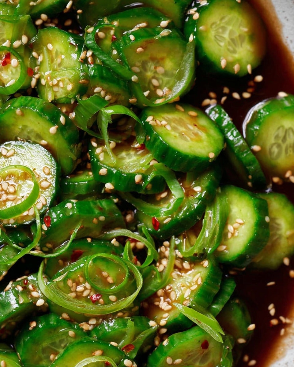 The image shows thick, bright green cucumber slices arranged closely together, almost piled up on a white marbled surface. The cucumbers have a wet shine and some have thin slices of green onion layered on top. The dish is sprinkled evenly with light beige sesame seeds and small red chili flakes, creating contrast. The sauce beneath the cucumbers is dark brown, glossy, and slightly pooled around the edges of the cucumber slices, adding depth to the image. The overall look is fresh, vibrant, and textured. photo taken with an iphone --ar 4:5 --v 7