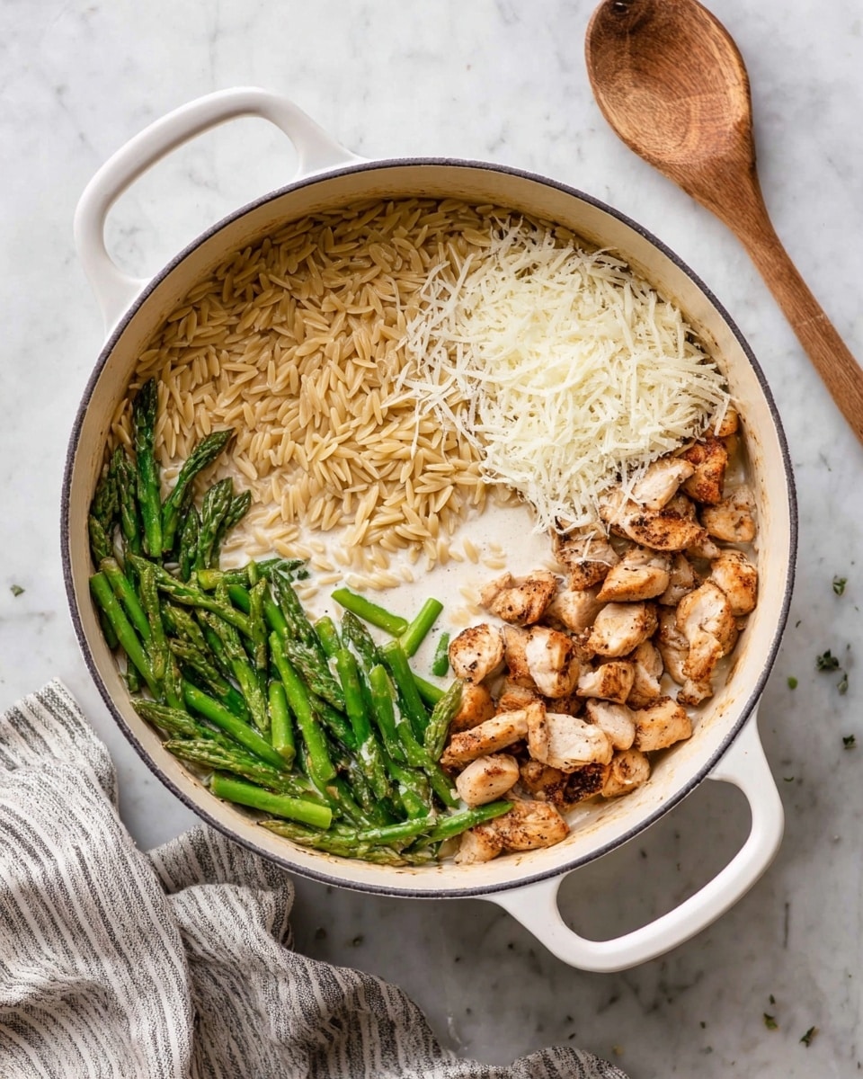The image shows a white pot with two handles filled with four distinct sections of food. Starting from the bottom is a layer of cooked orzo pasta in a light golden brown color, covering the pot base. On the right side above the orzo is a creamy white sauce partially soaking the pasta. Near the top right is a generous mound of shredded white cheese. On the left side is a pile of green asparagus pieces, sliced diagonally and roasted or steamed. Along the bottom right edge on top of the orzo are browned, bite-sized pieces of cooked chicken. The pot is placed on a white marbled surface with a wooden spoon and a striped cloth nearby. photo taken with an iphone --ar 4:5 --v 7