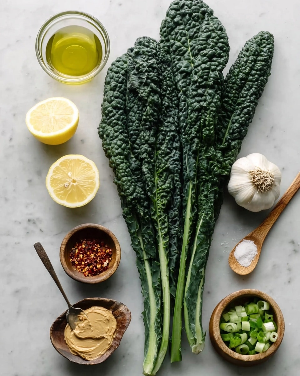 The image shows several fresh ingredients arranged neatly on a white marbled surface. On the left side, there are four long, dark green kale leaves with a bumpy texture and thick light green stems. To the top right of the kale are two whole garlic bulbs with a white papery outer layer. Below them is a small clear glass bowl filled with a pale yellow liquid, likely oil. Next to it are two lemon halves with bright yellow skin and juicy interiors. Below the lemons is a small wooden bowl filled with crushed red chili flakes. To the bottom right of the kale is a wooden spoon holding a tan-colored paste. Below it, a small wooden spoon rests with a pinch of white salt. At the bottom right corner, another wooden bowl contains chopped green onions. The overall look is fresh and organized. photo taken with an iphone --ar 4:5 --v 7