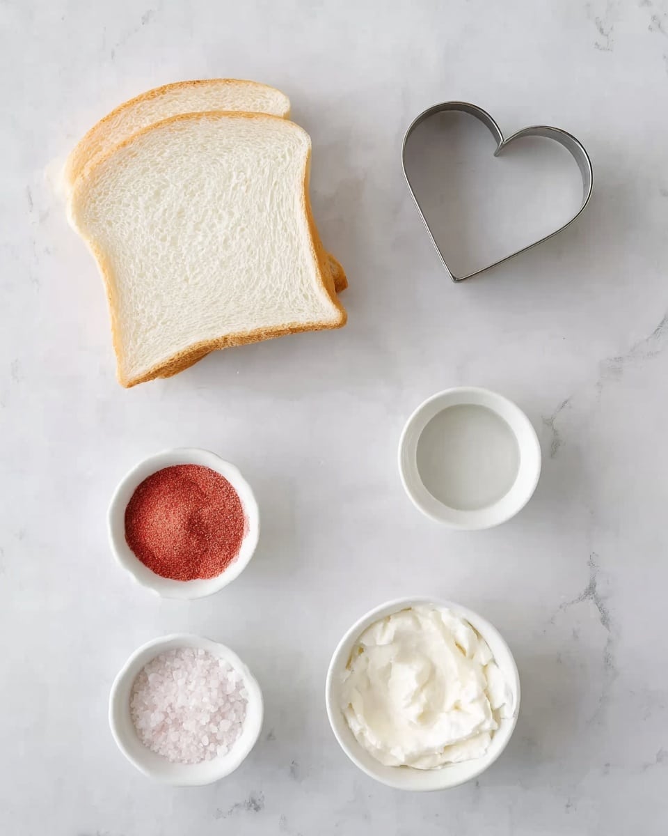 The image shows three slices of white bread stacked on a white marbled surface on the left side, with a small heart-shaped metal cookie cutter above the bread. Surrounding the bread are four small white bowls: one bowl contains a clear liquid, another has white creamy substance, the third bowl holds a pink powder, and the last bowl contains white granulated sugar. The layout is neat and minimal with a bright, soft light. photo taken with an iphone --ar 4:5 --v 7