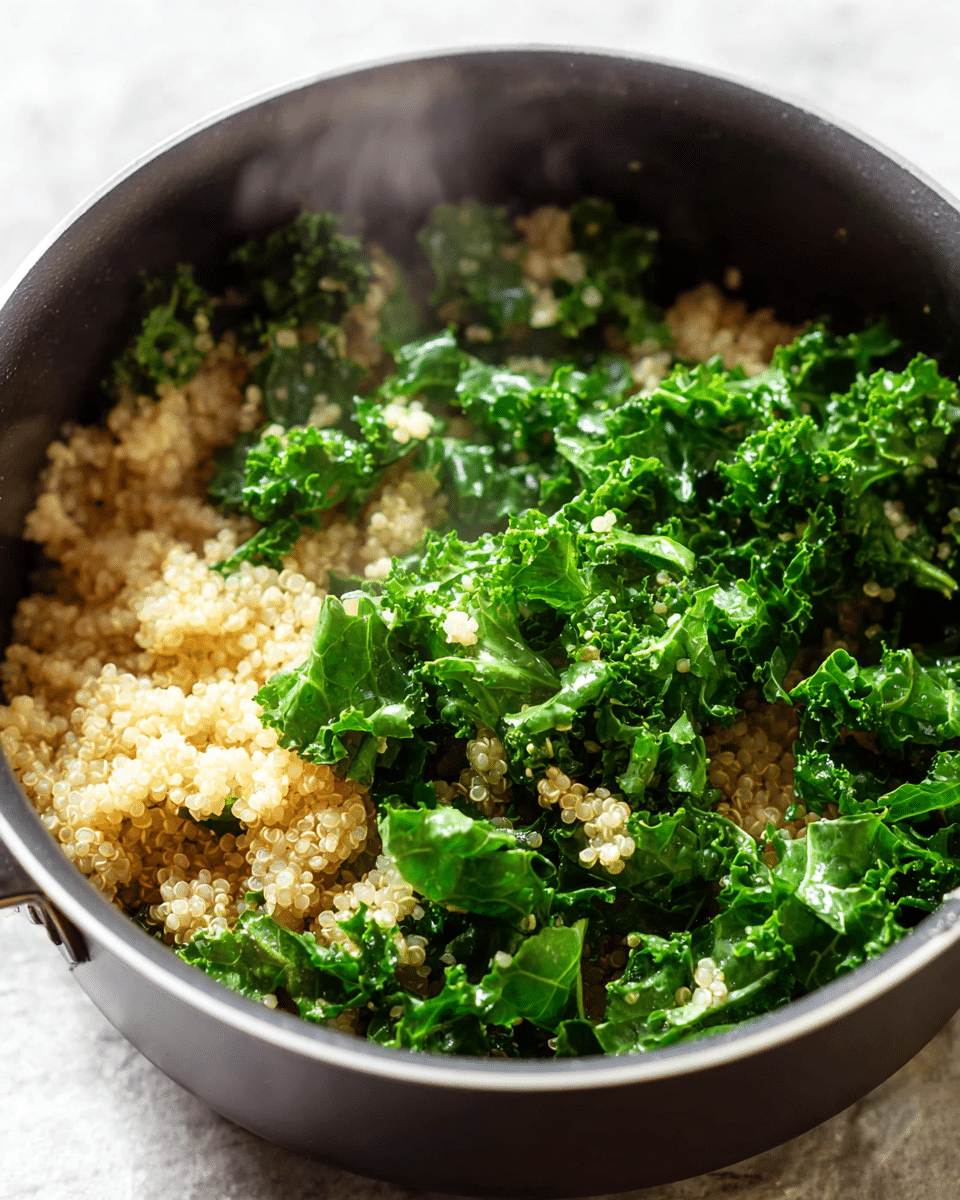 A close-up view of a black pot filled with two main layers: the bottom layer is light beige cooked quinoa with a soft, fluffy texture, and the top layer is bright green fresh kale leaves with a crinkled texture scattered evenly on the quinoa. The pot sits on a white marbled surface. Steam is gently rising from the food, showing it is hot. Photo taken with an iphone --ar 4:5 --v 7