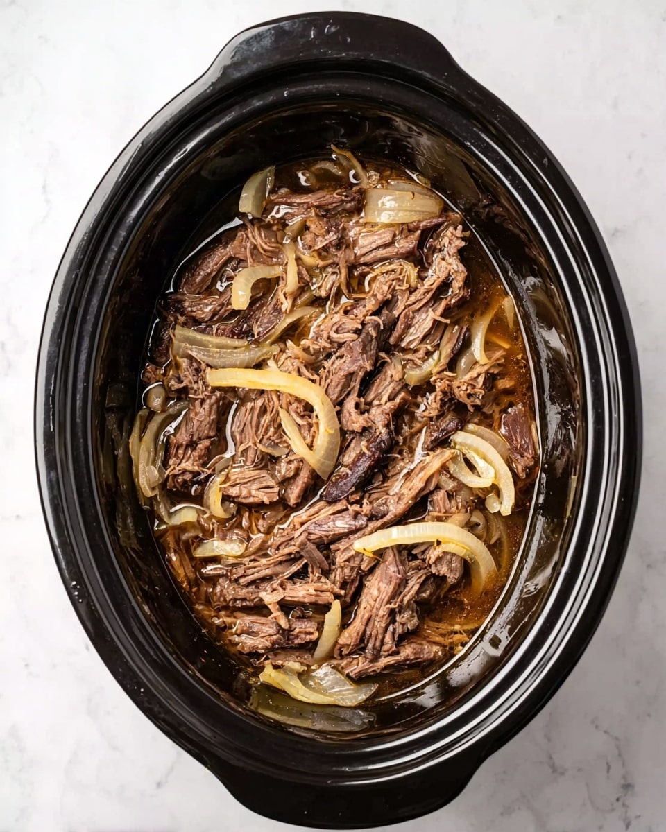 The image shows a black oval slow cooker filled with shredded brown cooked meat mixed with soft, translucent, light yellow onion slices scattered evenly on top and throughout. The meat looks moist and tender, sitting in a shallow pool of glossy brown juices. The slow cooker is placed on a white marbled surface. photo taken with an iphone --ar 4:5 --v 7