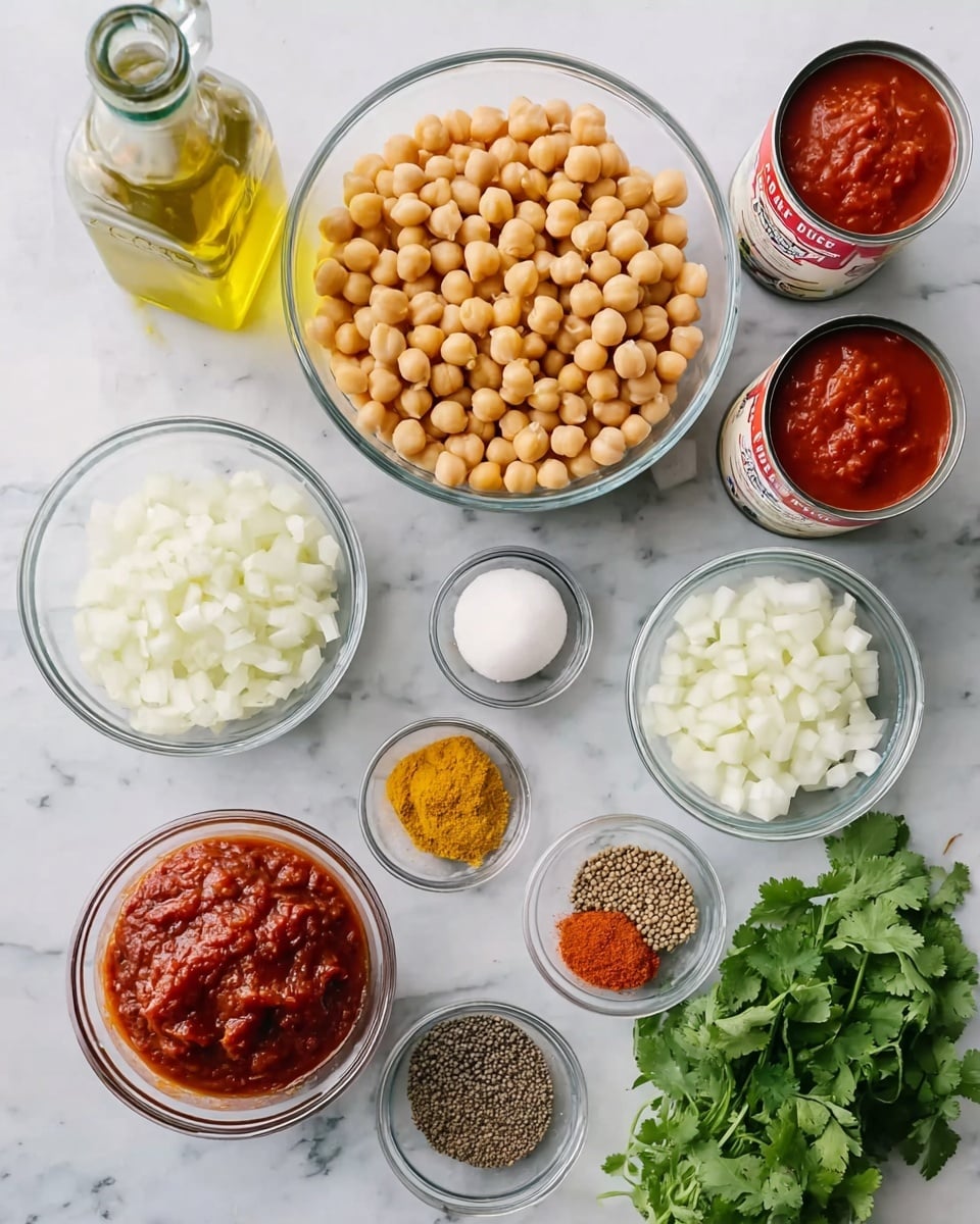 A top-down view of various ingredients arranged neatly on a white marbled surface: in the center, a clear glass bowl filled with light brown chickpeas; above to the left, a glass bottle with light yellow olive oil; to the upper right, two open cans with red crushed tomatoes; below the chickpeas, a clear glass bowl of chopped white onions; to the right of the onions, two small clear glass bowls with minced garlic and another minced ingredient; below these, a small bowl of thick red paste; to the left below the onions, a small bowl of colorful ground spices including deep yellow turmeric and reddish brown powders; next to that, a small bowl of cumin seeds; and on the bottom right corner, fresh green cilantro leaves resting on the surface. Photo taken with an iphone --ar 4:5 --v 7
