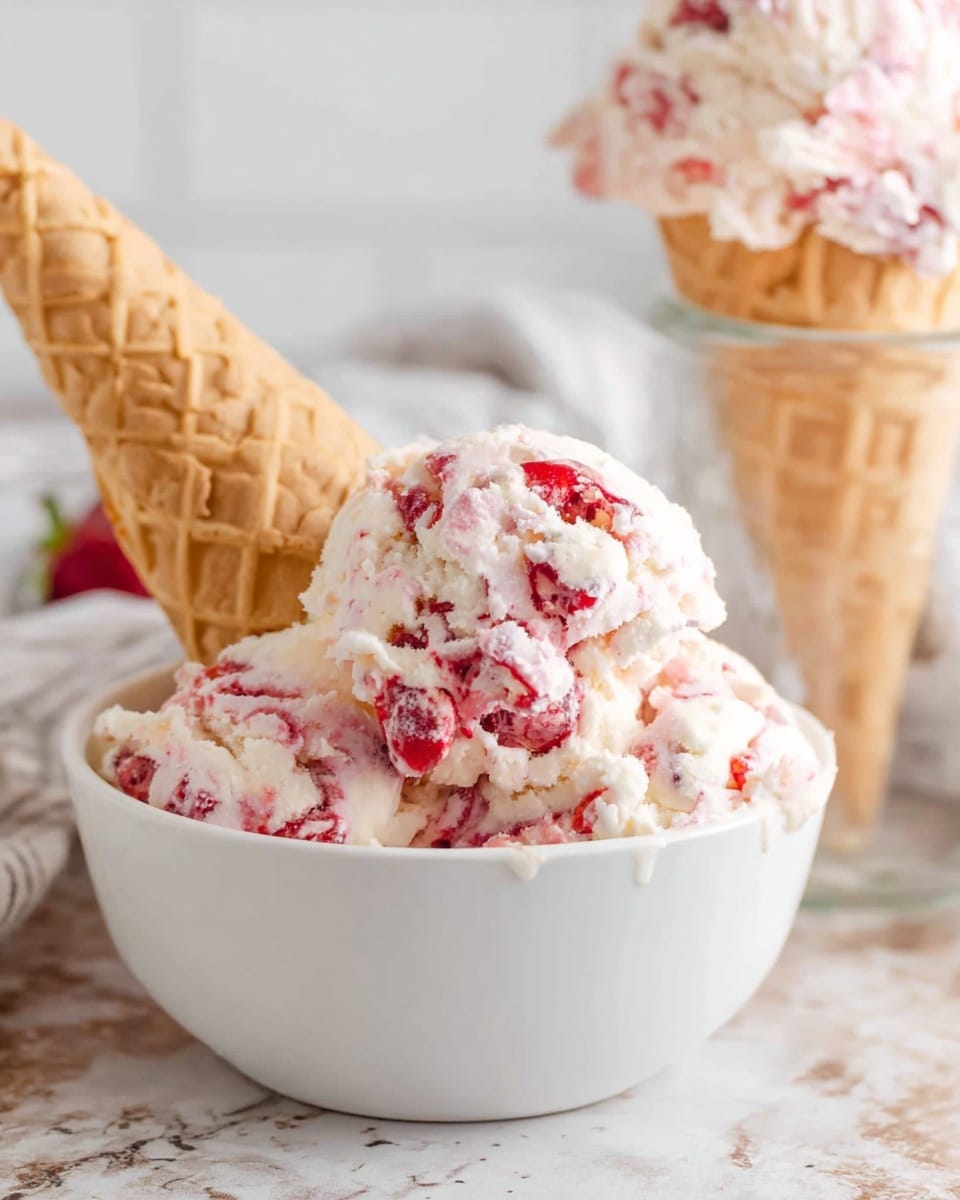 The image shows a white small bowl filled with white and pink swirled ice cream with chunks of strawberry mixed in. A light brown waffle cone is placed upside down, sticking into the ice cream inside the bowl. In the background, there is another scoop of the same ice cream in a white waffle cone, resting on a clear glass jar. The setting is on a surface with white marbled texture and a blurred white and gray cloth is visible behind the bowl. The colors are soft and natural, with the ice cream looking creamy and rich. photo taken with an iphone --ar 4:5 --v 7