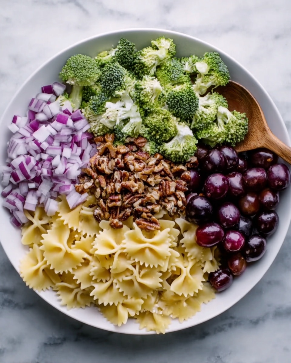 A white plate is placed on a white marbled surface. The plate is filled with six sections of food arranged like a color wheel. Starting from the left, there are chopped red onions with light purple and white colors. Below that, fresh green broccoli florets are neatly piled. In the middle top is a mound of chopped brown nuts with a rough texture. To the right of the nuts, there is pale yellow farfalle pasta with a smooth, slightly ridged surface. Below the pasta are shiny dark purple grapes, some whole and some sliced. A wooden spoon is resting on the pasta section near the plate edge. Photo taken with an iphone --ar 4:5 --v 7