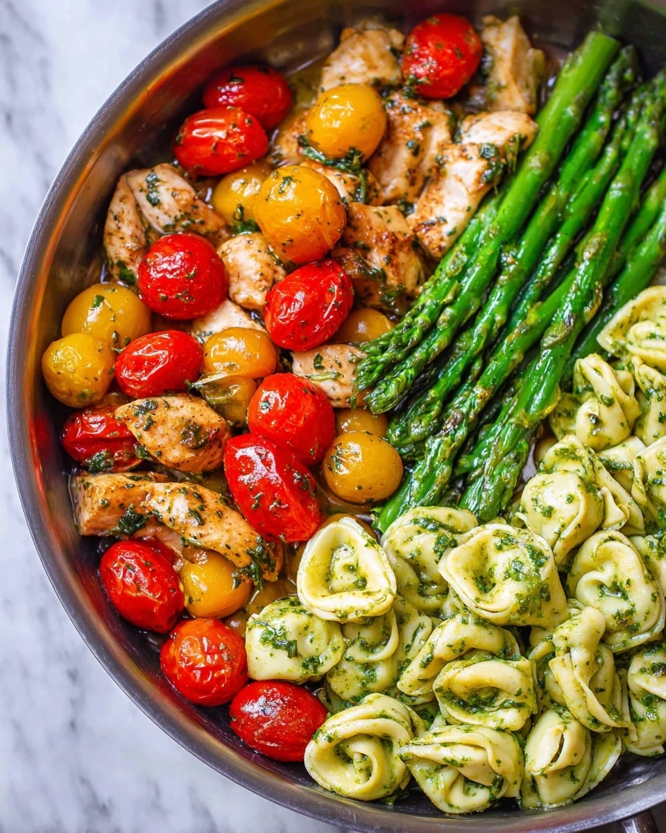 A metal pan filled with three main layers: on the left, pieces of cooked chicken mixed with halved red and yellow cherry tomatoes, glistening with herbs and oil; in the middle, bright green cooked asparagus spears arranged in a neat bundle running vertically; on the right, a serving of tortellini pasta coated in a green herb sauce, folded and shiny. The white marbled surface is partly visible around the pan, and soft natural light highlights the textures and colors beautifully. Photo taken with an iphone --ar 4:5 --v 7