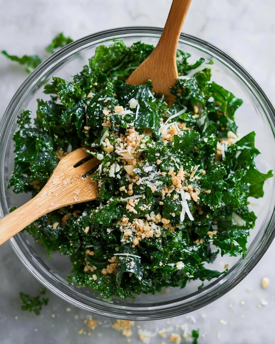 A clear glass bowl filled with fresh, dark green kale leaves that have a slightly crinkled texture, mixed with small amounts of light beige breadcrumbs and thin white shreds of cheese scattered on top. Two wooden forks are placed inside the bowl, one on the left and one on the right, partially buried in the kale. The bowl sits on a white marbled surface with some crumbs scattered around it. Photo taken with an iphone --ar 4:5 --v 7
