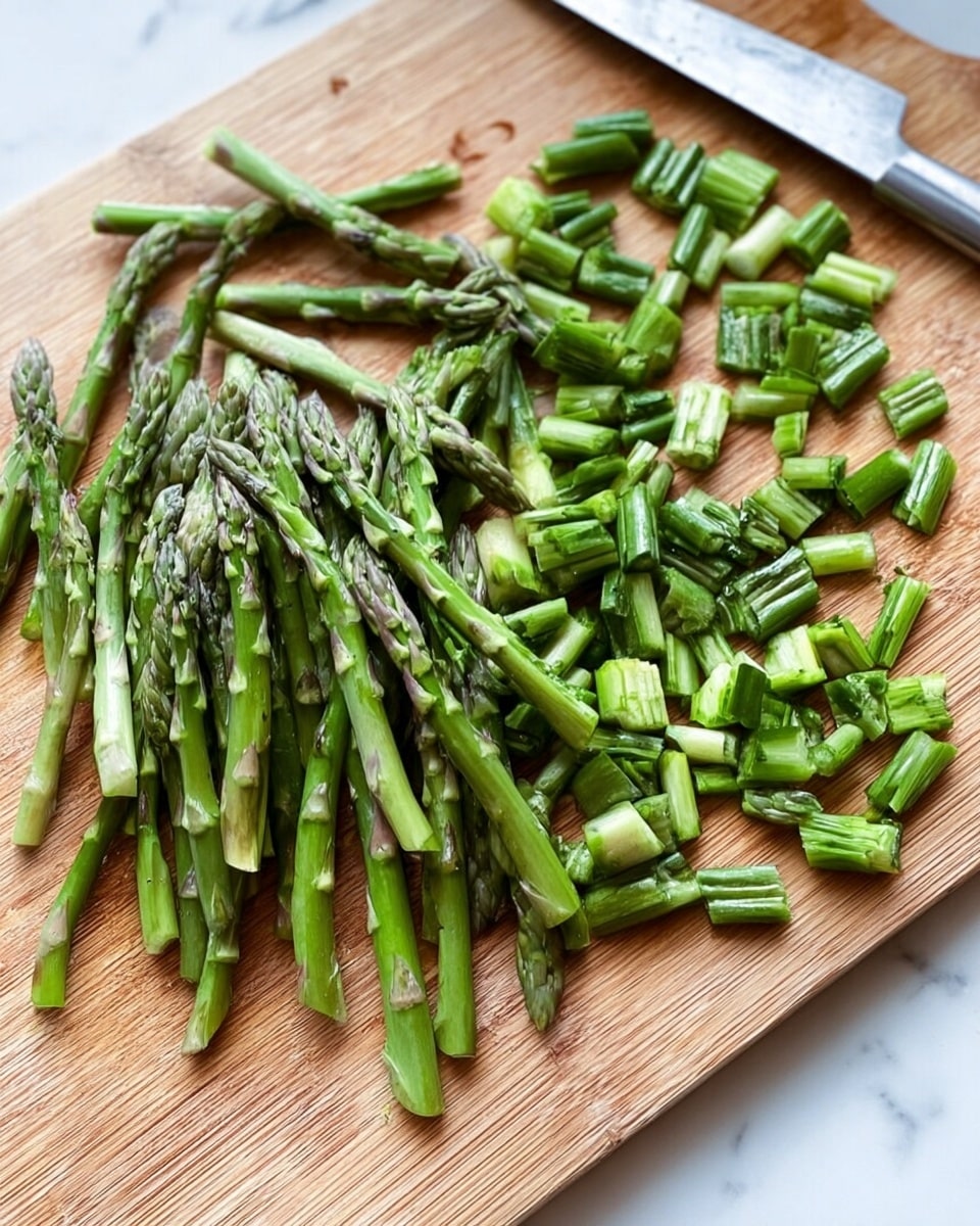A pile of green asparagus spears is shown on a wooden cutting board. The asparagus is cut into two parts: the thicker bottom stems are chopped into small, even short pieces lying on the right side, while the thinner, pointed tops remain whole and spread out on the left side. A silver knife rests on the upper right corner of the board. The whole scene is set on a white marbled surface. photo taken with an iphone --ar 4:5 --v 7