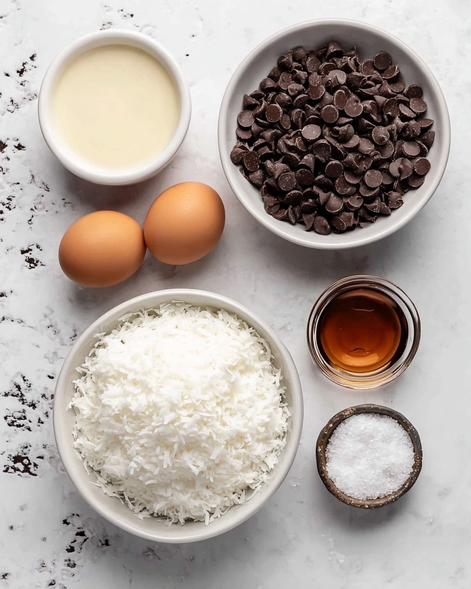 The image shows six white bowls and a small container arranged on a white marbled surface. The largest bowl at the bottom center is filled with white shredded coconut flakes, showing a fluffy and textured layer. Above it to the right, a medium white bowl contains a heap of dark brown chocolate chips, smooth and shiny with a slightly rounded shape. To the left of the chocolate chips, a smaller white bowl holds light cream-colored liquid, smooth and creamy in texture. Above this, a very small white bowl has two brown eggs, smooth and matte. To the bottom right of the chocolate chips, a tiny glass bowl holds light brown liquid vanilla extract, clear with a glossy surface. Next to it is a small round container with coarse white salt. The bowls and container sit neatly on the white marbled background with some dark speckles. Photo taken with an iphone --ar 4:5 --v 7