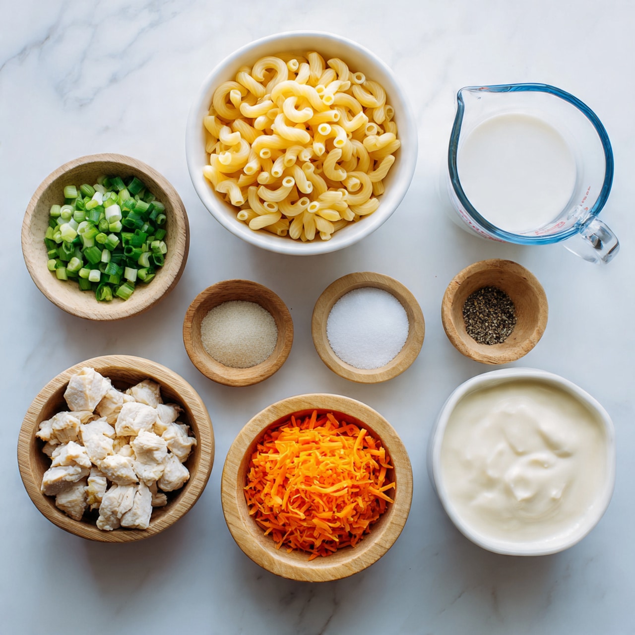 The image shows a collection of ingredients arranged neatly on a white marbled surface. There are eight bowls and a measuring cup, all white or wooden except the cup which is clear with a blue rim. The largest white bowl at the top left holds uncooked yellow elbow macaroni pasta with a smooth texture. To its right, a clear measuring cup contains white milk. Below the milk are three small wooden bowls with salt, sugar, and black pepper. On the left side, there is a wooden bowl with chopped green onions and another wooden bowl filled with bright orange shredded carrots. At the bottom left, a wooden bowl is filled with small pieces of cooked pale light chicken. Finally, a white bowl at the bottom right holds creamy, smooth off-white cheese or sauce. The setup is clean and organized, ready for cooking photo taken with an iphone --ar 4:5 --v 7
