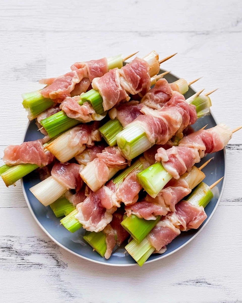 A round white plate sits on a white marbled surface, full of several wooden skewers holding pieces of raw light pink meat layered with green and white stalks of green onion. Each skewer has three layers: a piece of green onion at the bottom, a folded cluster of pinkish raw meat with some light yellow fat in the middle, and another piece of green onion near the top. The colors are light pink, green, and white, with textures showing the soft raw meat and firm green onion. The plate is viewed from above, showing the uniform arrangement of skewers overlapping slightly. Photo taken with an iphone --ar 4:5 --v 7